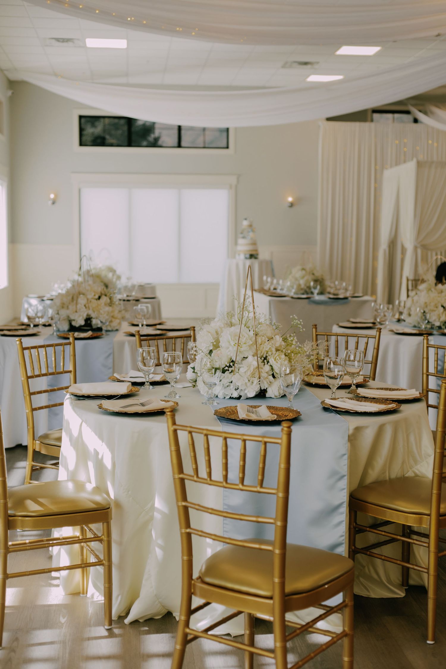 Elegant wedding reception setup with gold chiavari chairs and white table settings.