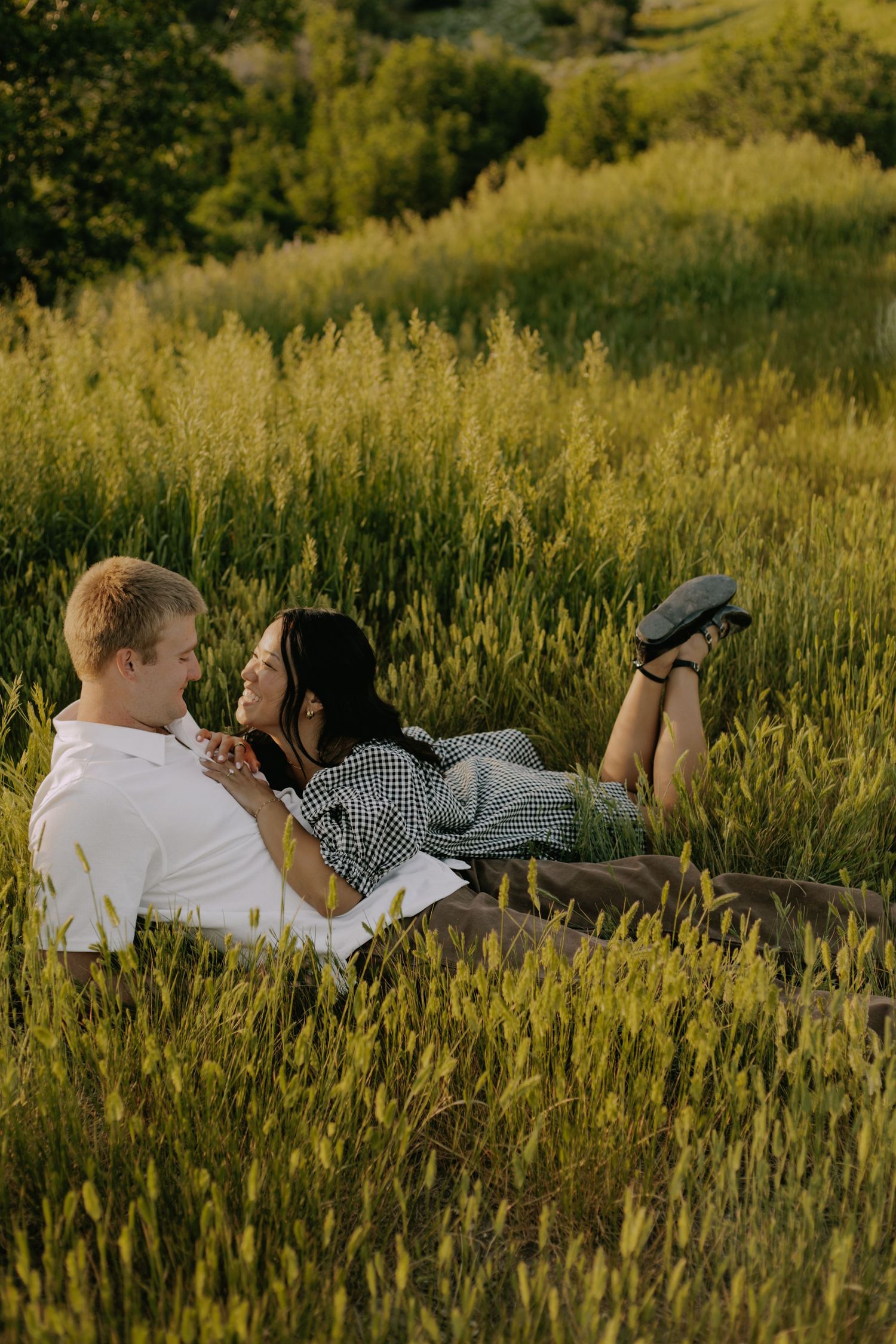 Two people lying in tall golden grass having an intimate conversation at sunset.