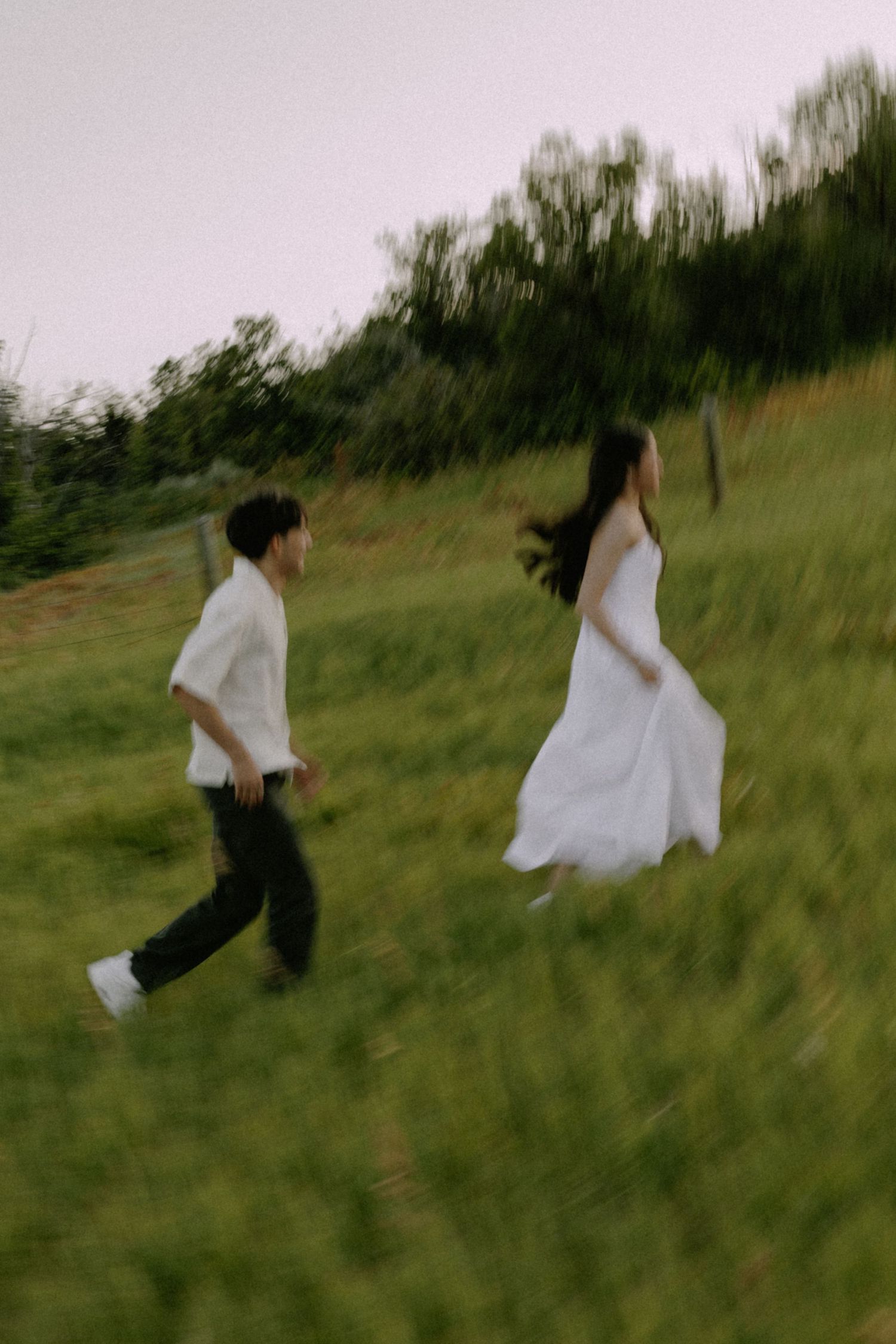 Motion-blurred figures running through tall grass in a playful scene.