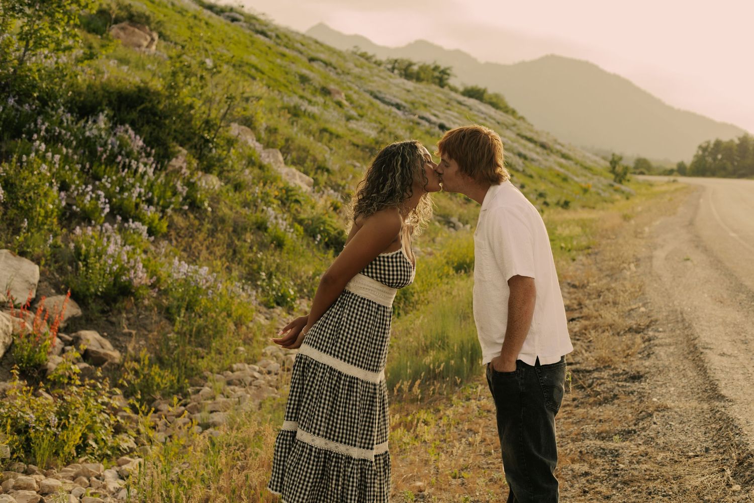 Couple shares romantic moments on a mountain trail surrounded by nature.