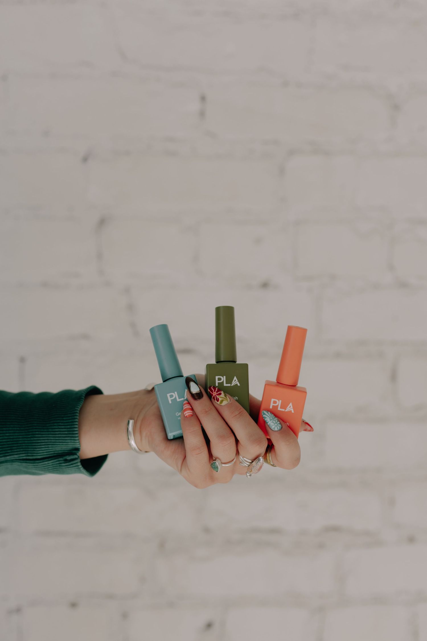 Hands displaying collection of colorful PLA bottles against white background.