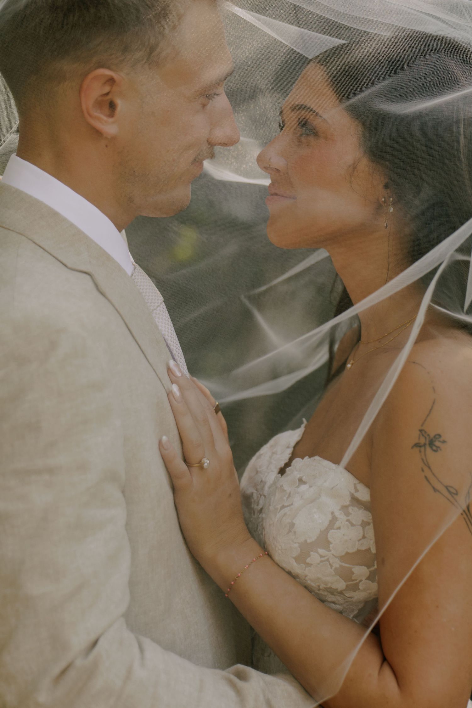Romantic wedding portrait of couple under a delicate veil.
