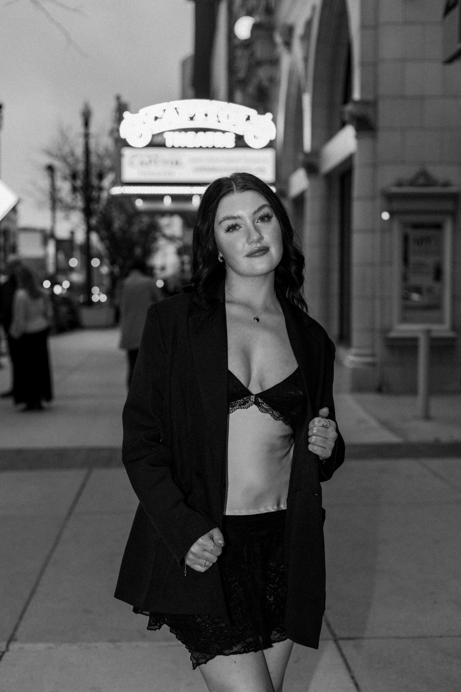 Black and white urban portrait featuring person in black jacket on city sidewalk.