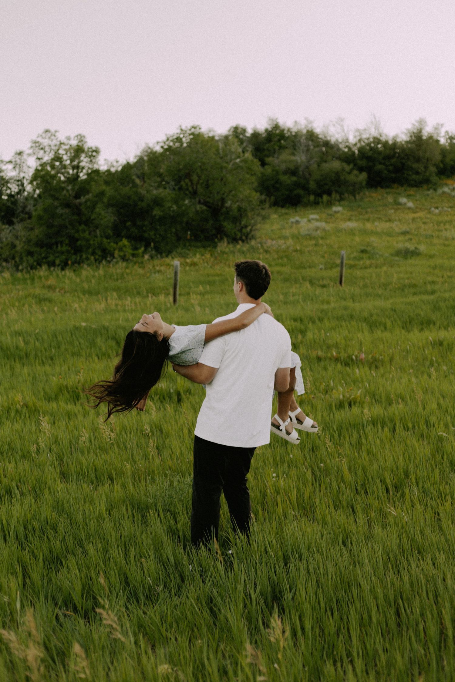 Two people running playfully through a lush green field.