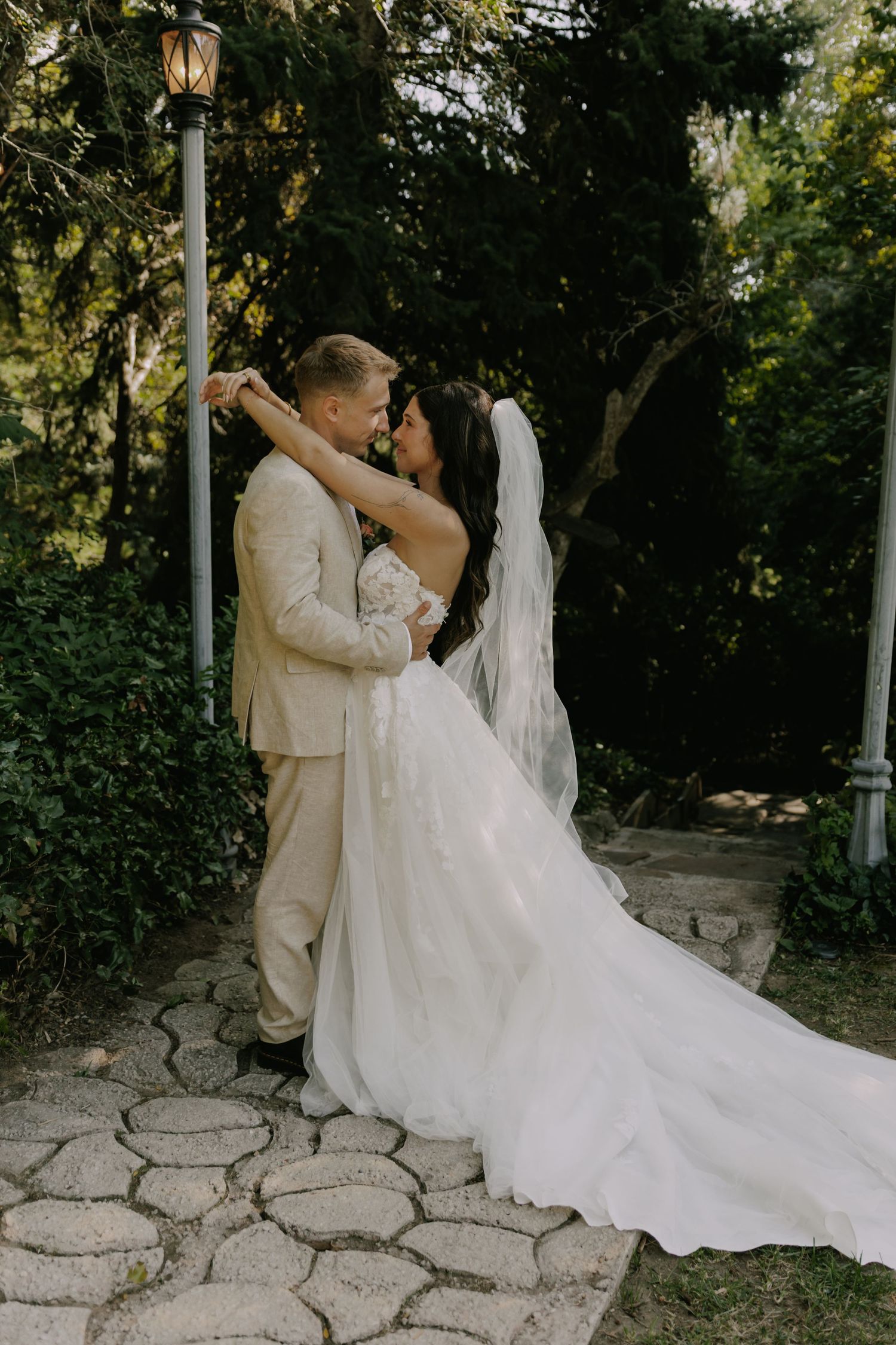Wedding couple dancing romantically on stone patio surrounded by greenery.