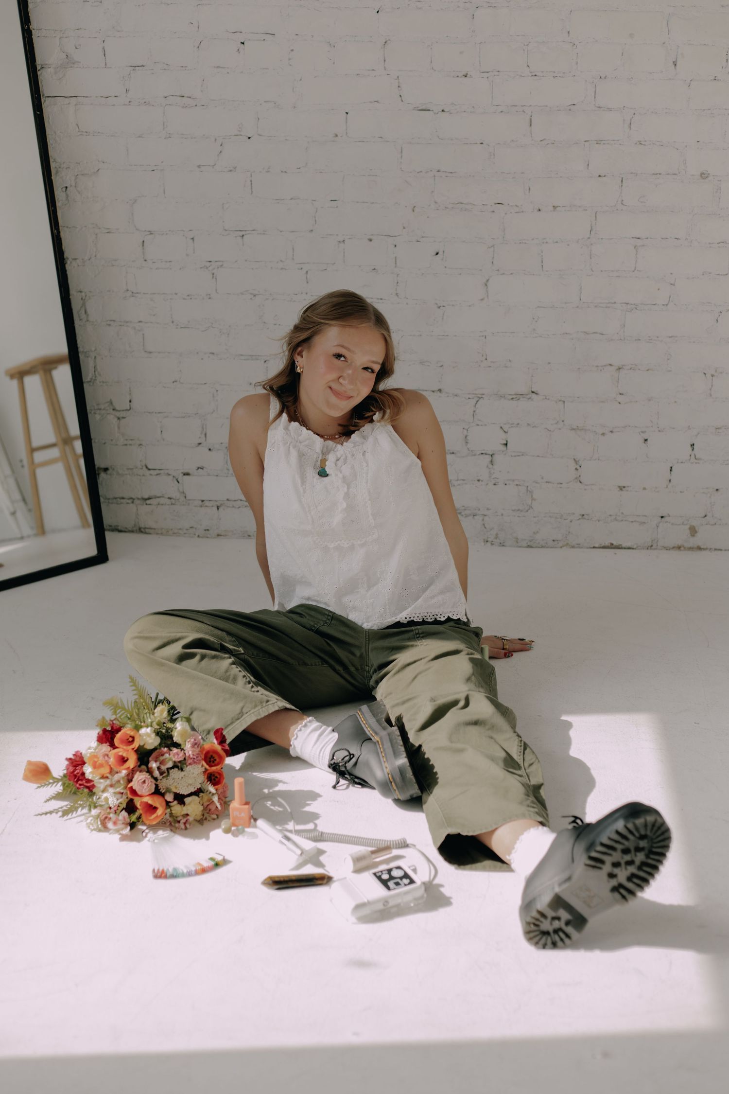 Lifestyle photo with flowers and accessories arranged on white floor in studio setting.