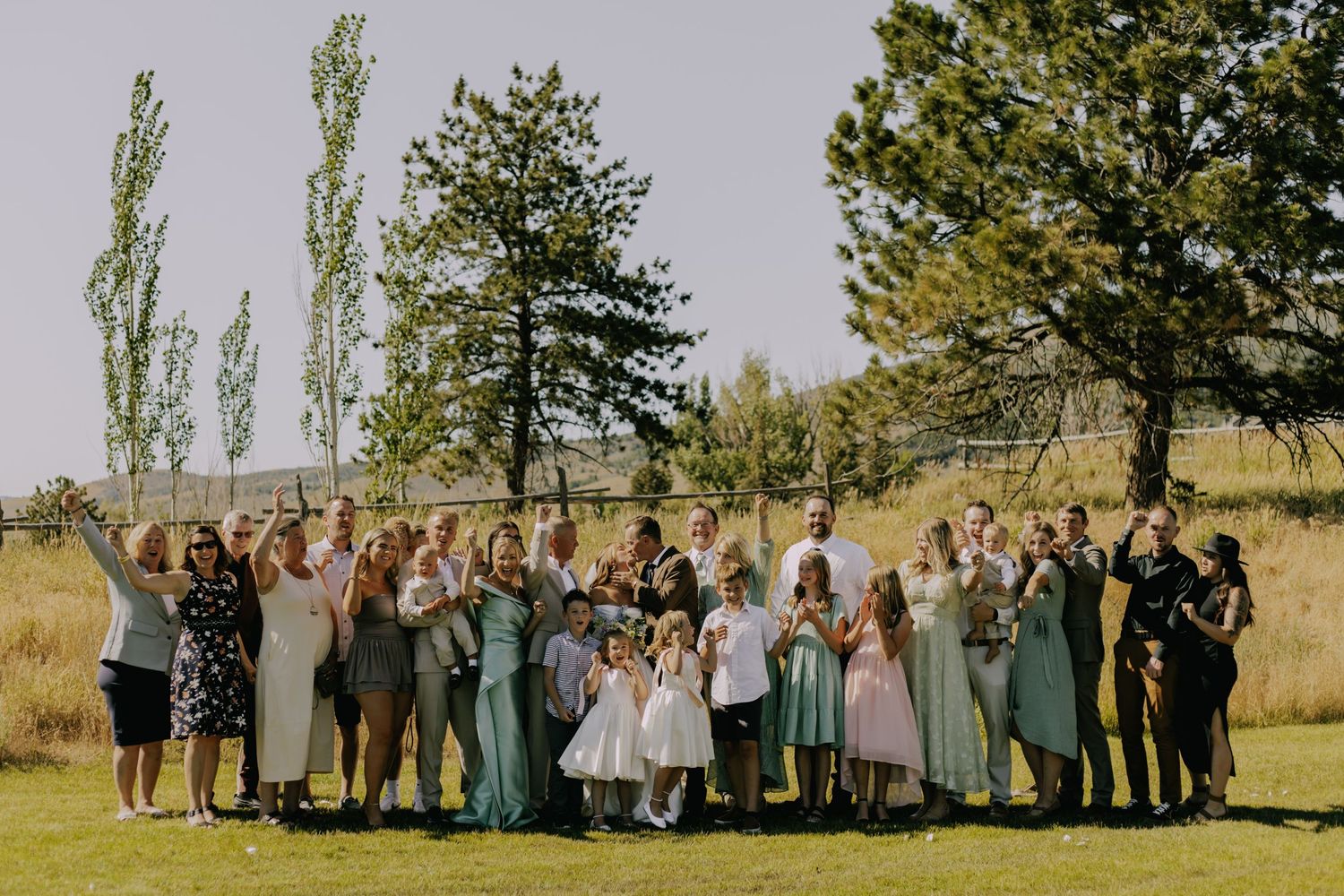 Wedding party group photo with bridesmaids and groomsmen lined up outdoors.