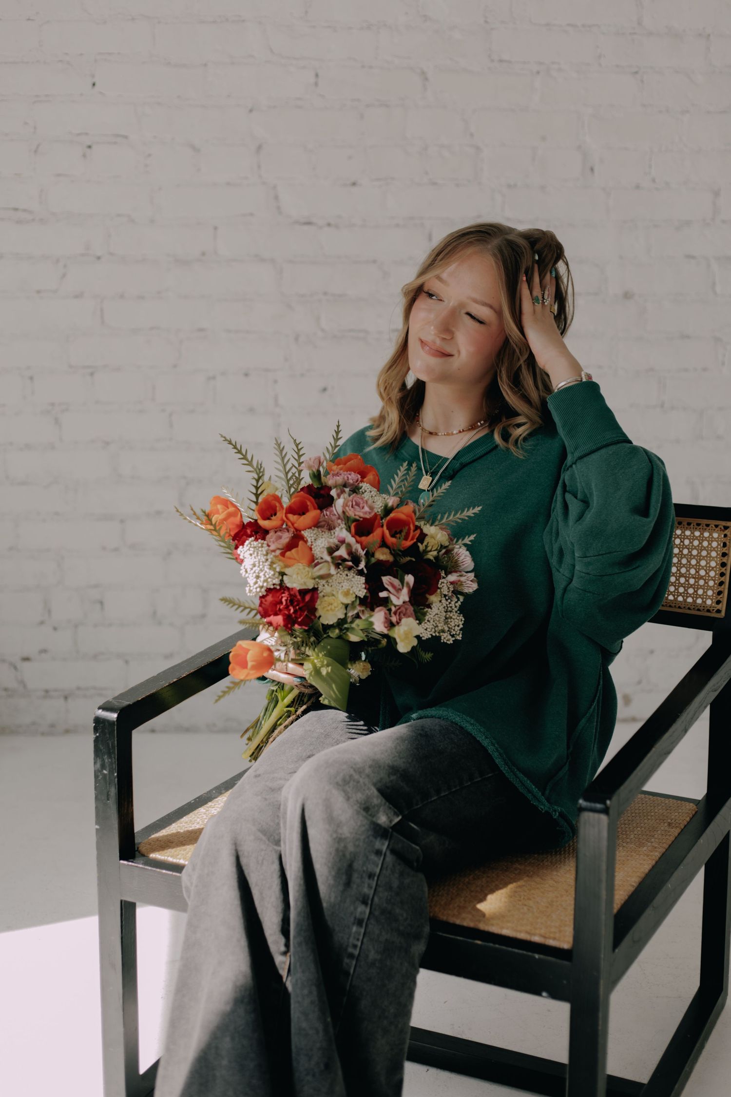 Person relaxing in modern chair with colorful flower arrangement nearby.