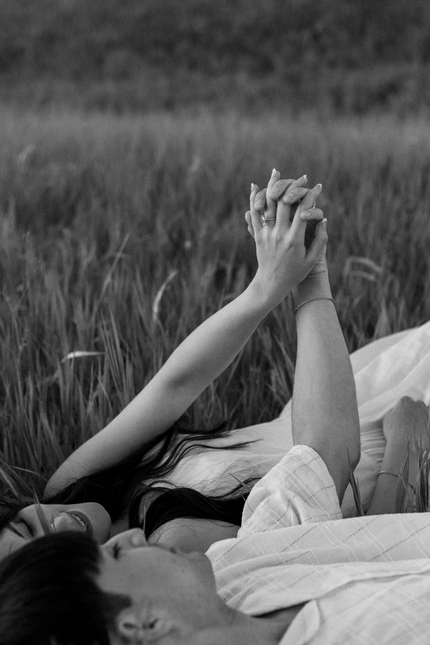 Black and white photo of hands raised against a dark sky in a field.