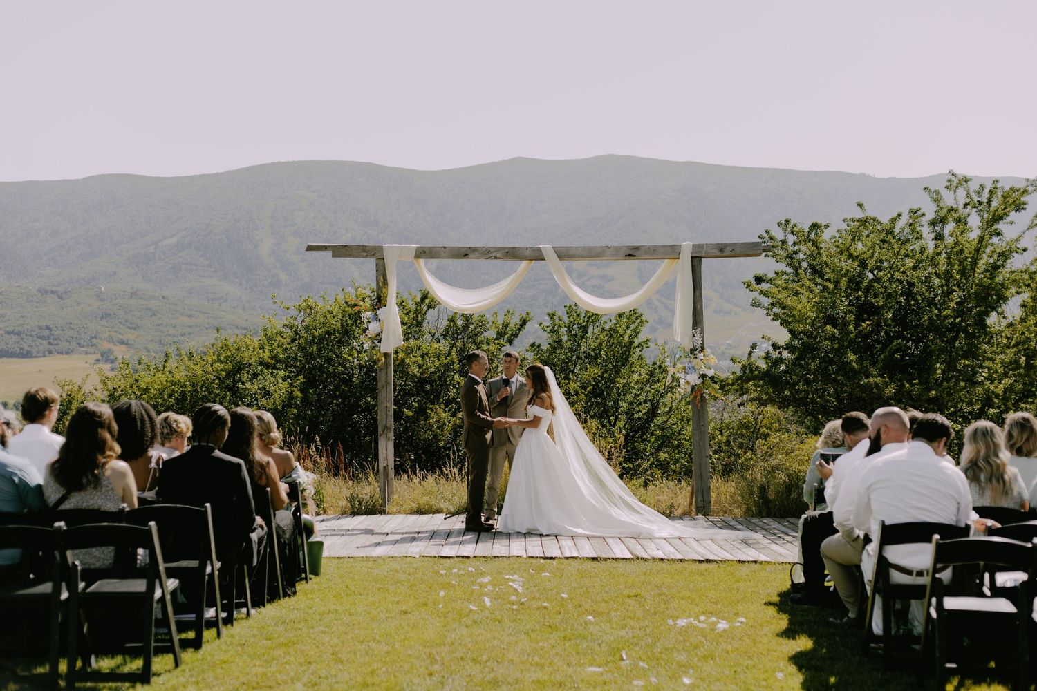 Outdoor wedding ceremony setup with chairs and mountain views in the background.