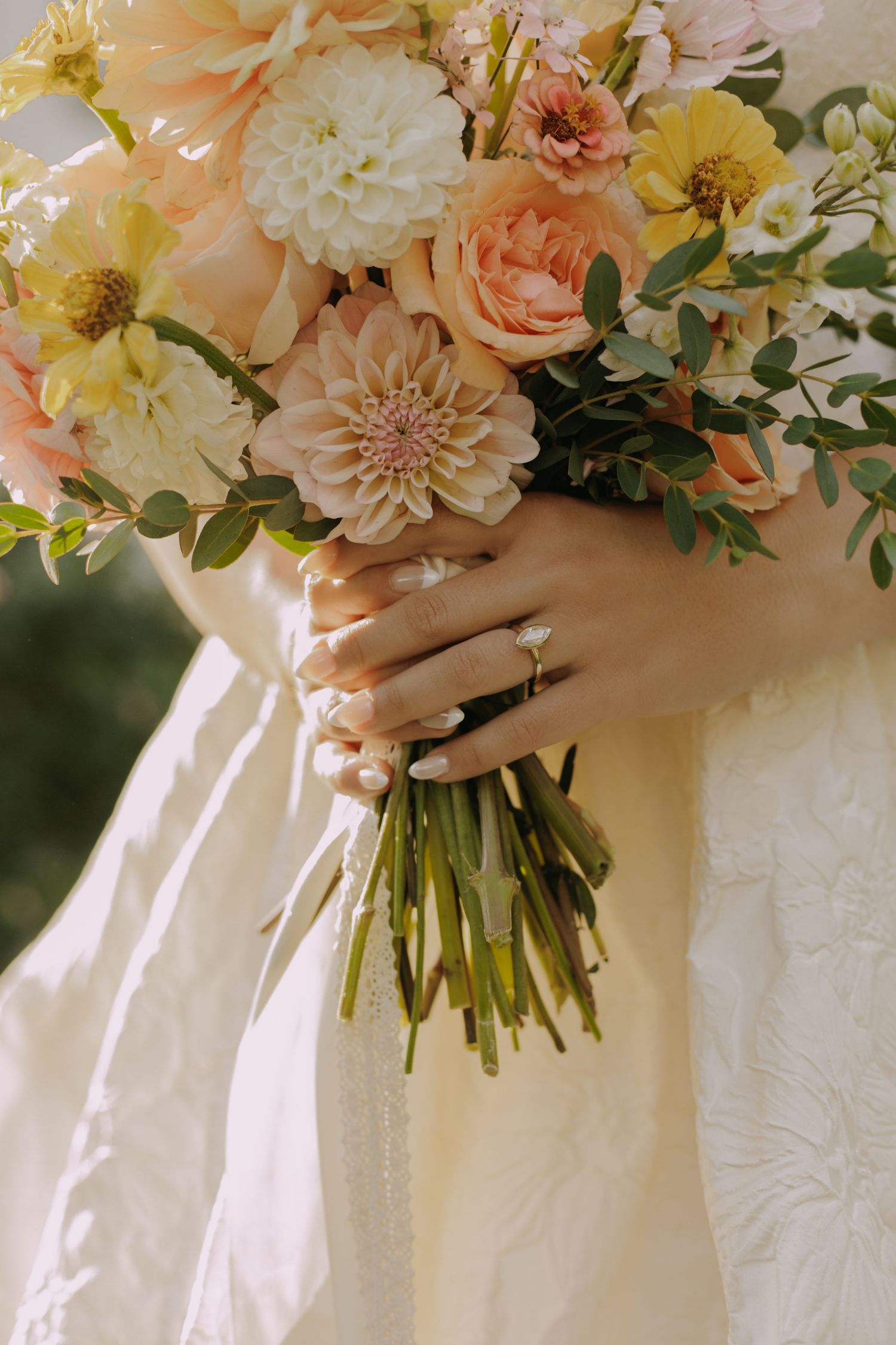 Delicate peach and cream floral bouquet with roses and dahlias tied with flowing ribbons.