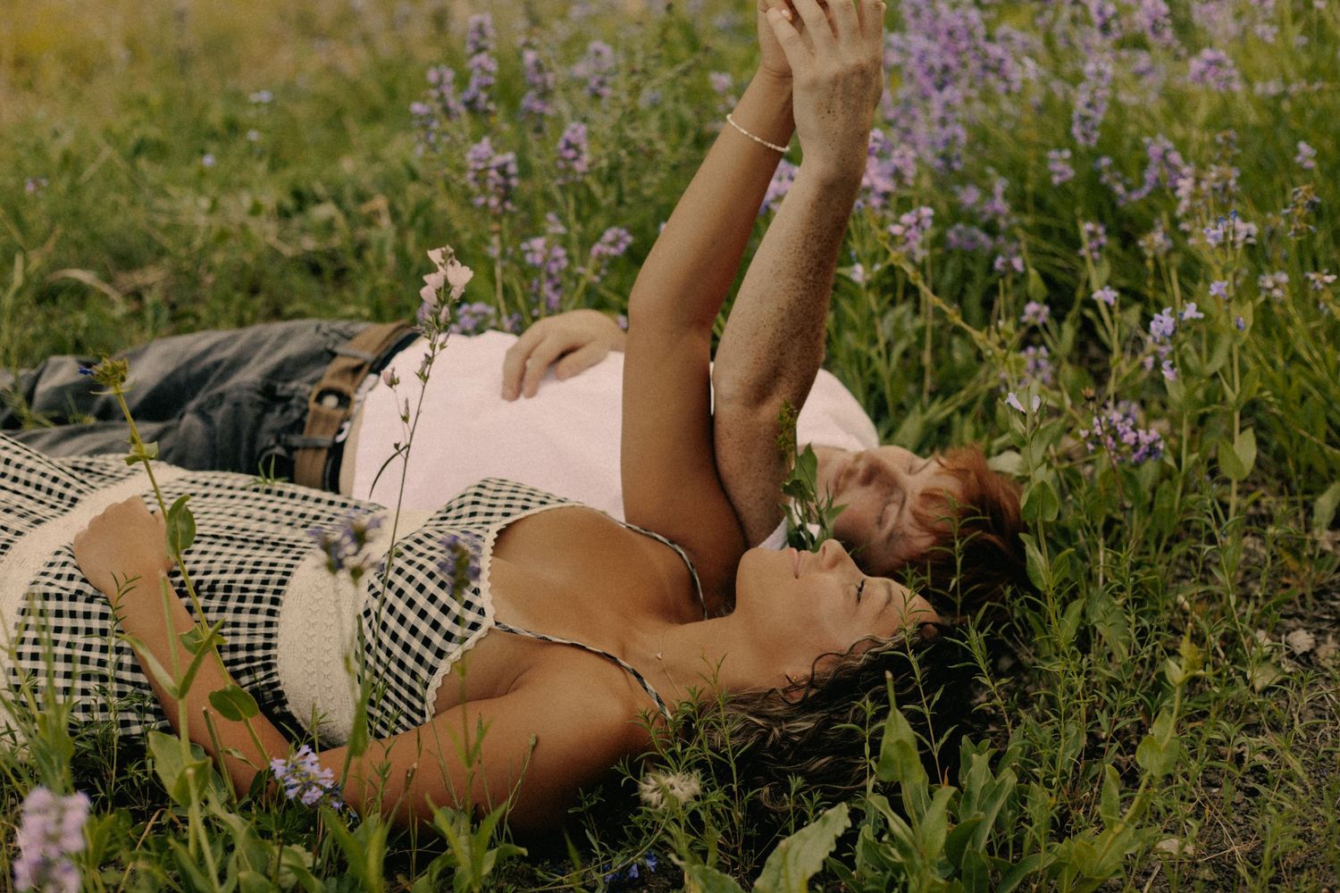 Person lying in field of purple wildflowers on sunny day.