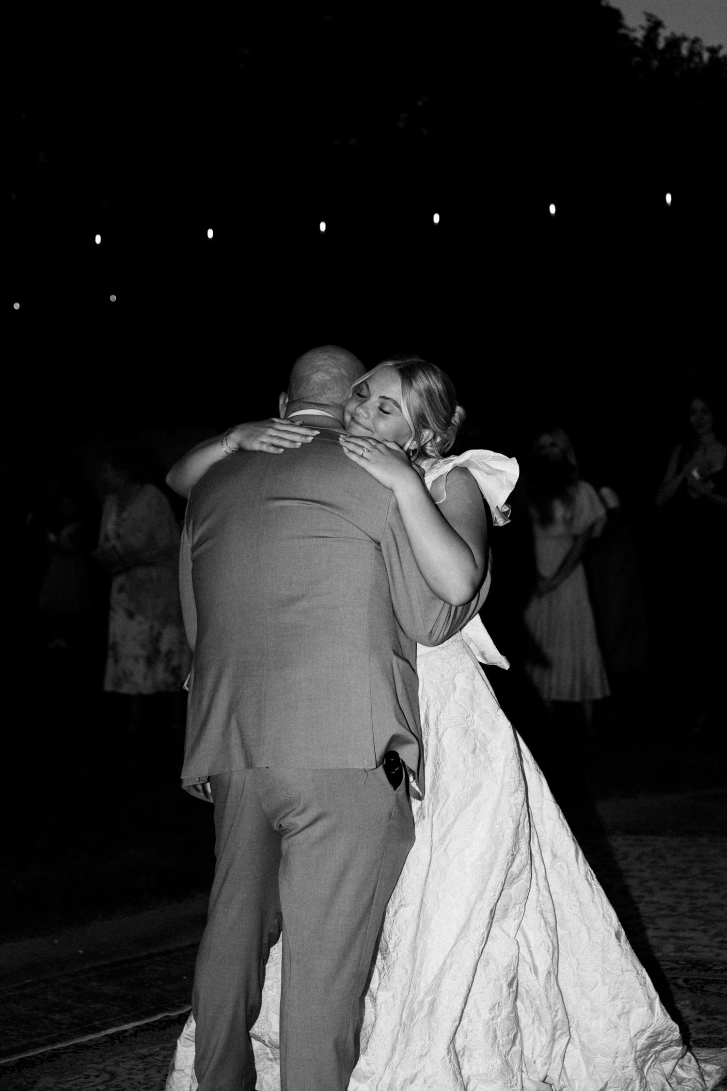 A couple embraces on a dark dance floor during their wedding celebration.