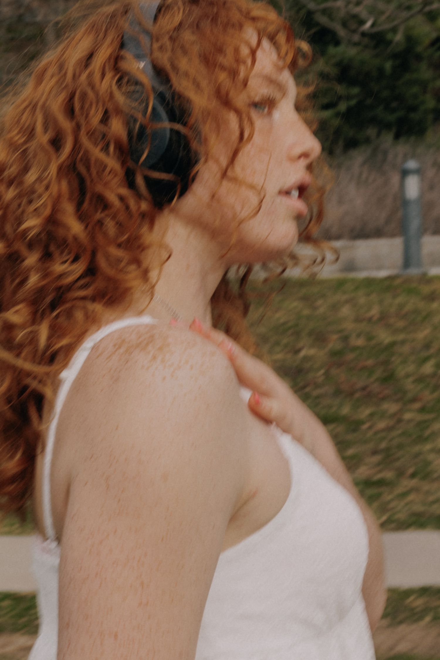 A side profile view of someone wearing a white tank top in natural lighting.