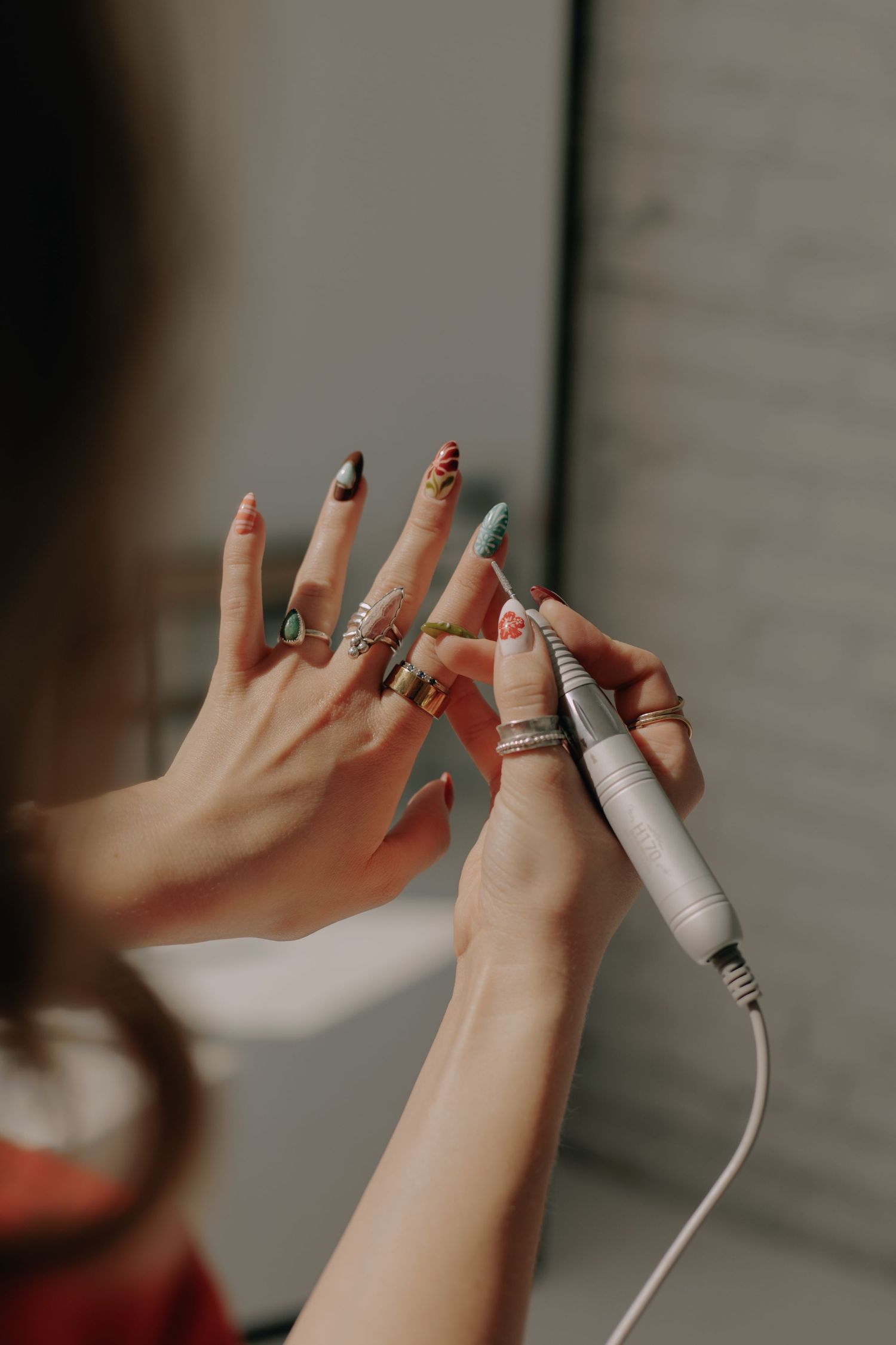 Close-up of hands wearing multiple rings while handling white electronic cords.