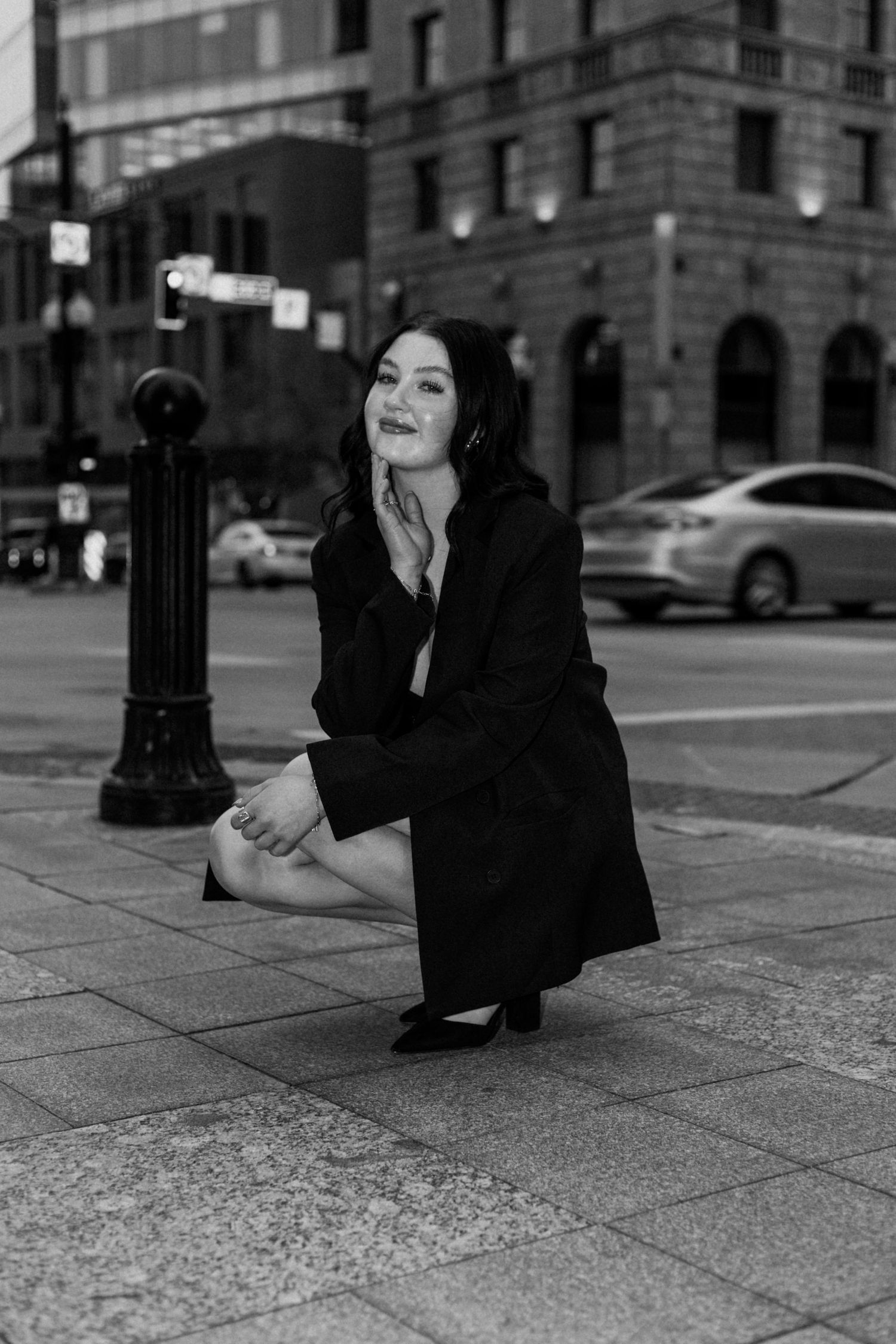 Artistic black and white portrait on city sidewalk with dramatic lighting.