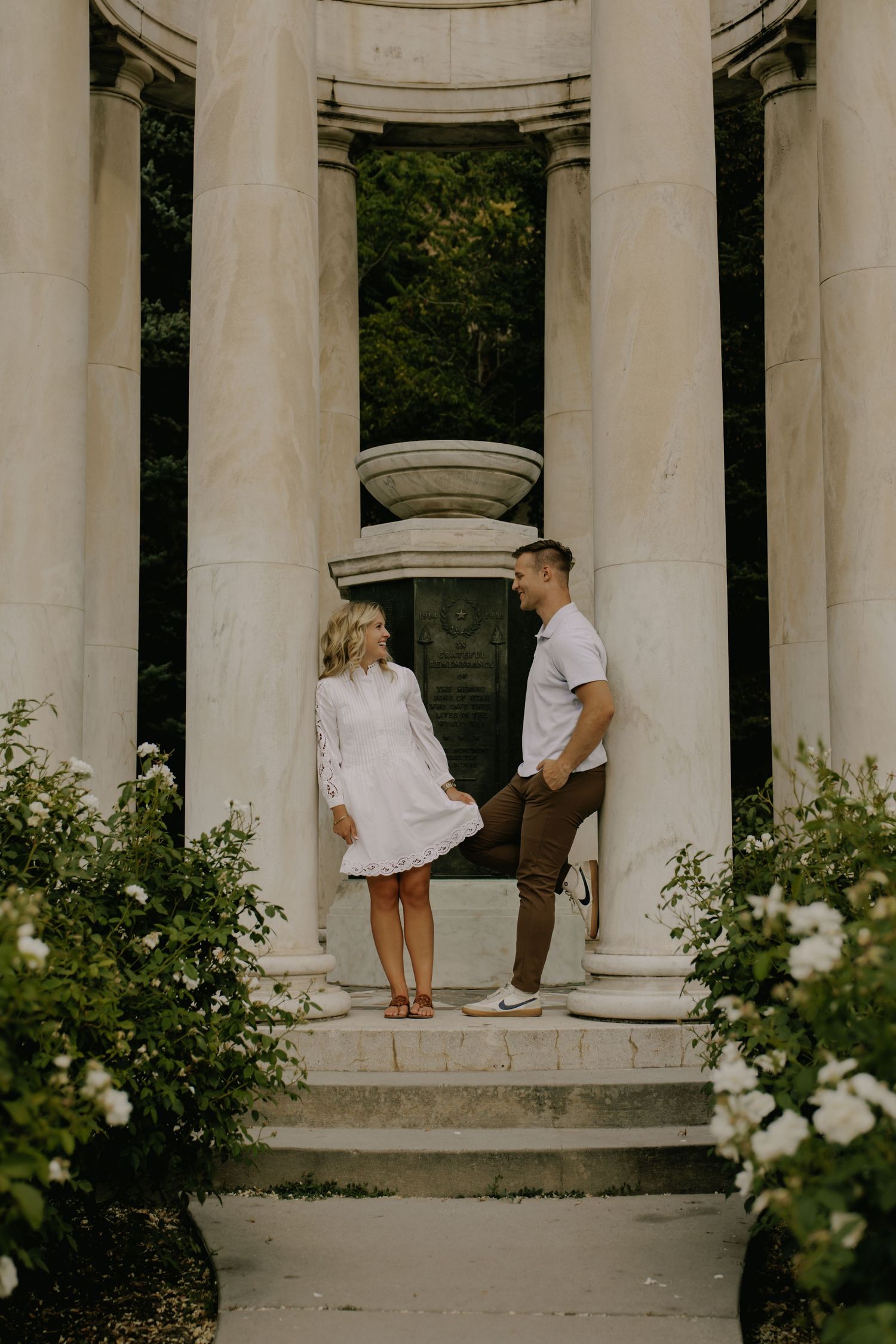 A romantic moment between two people in a classical white columned structure with roses.