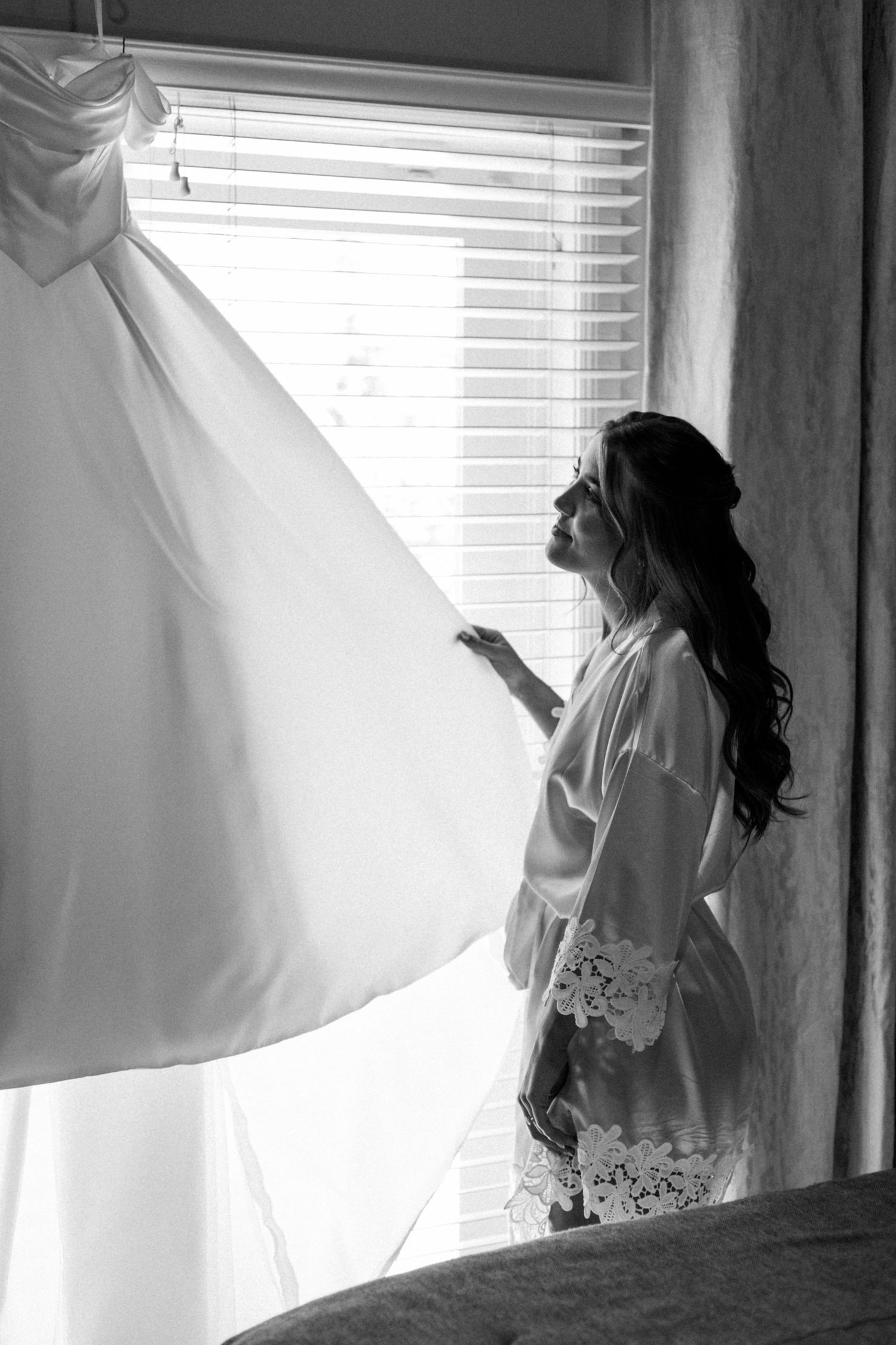 Artistic black and white photo of a bride silhouetted against bright windows.