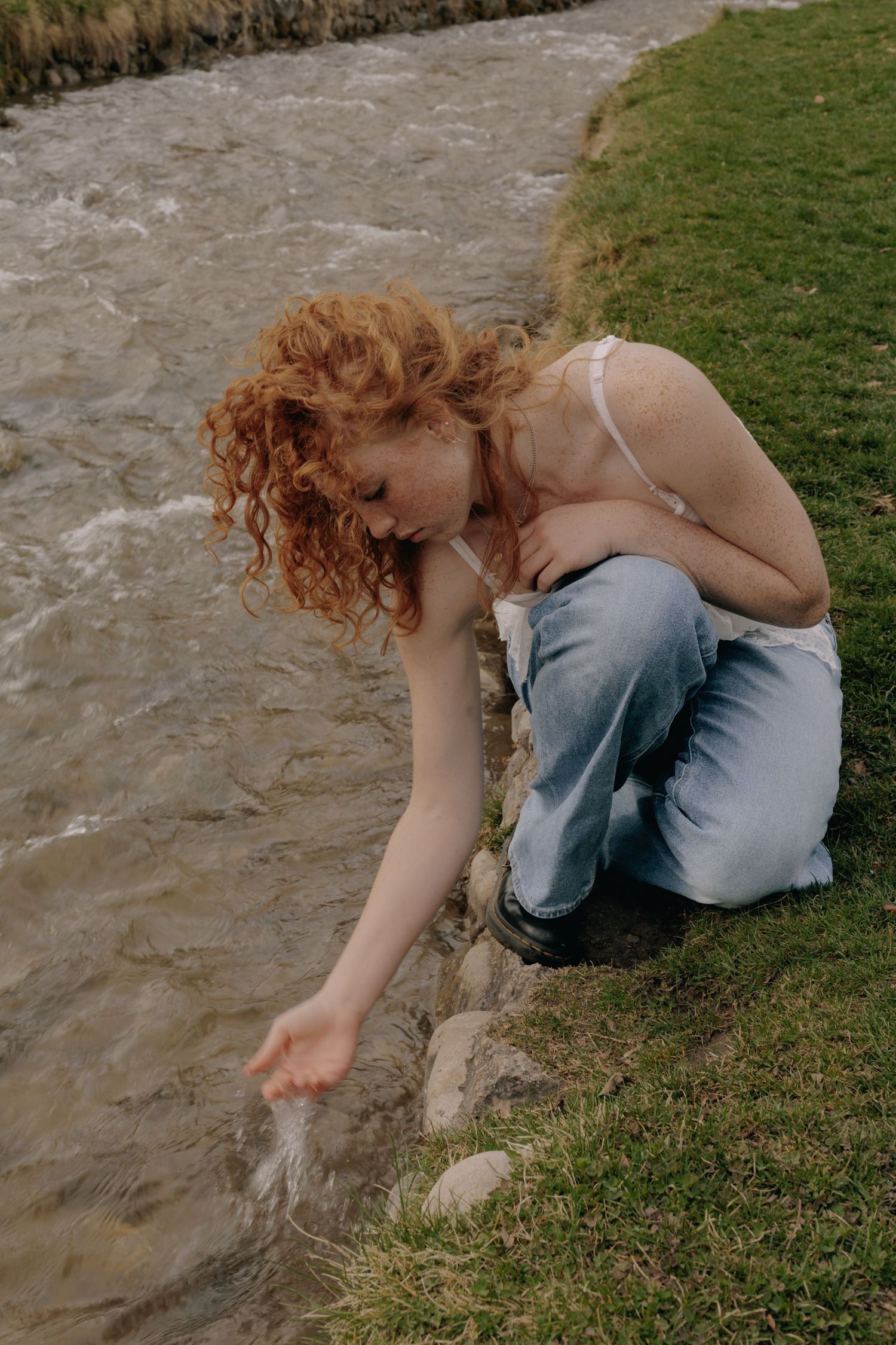 A sequence of photos showing someone reaching down to touch water by a grassy riverbank.