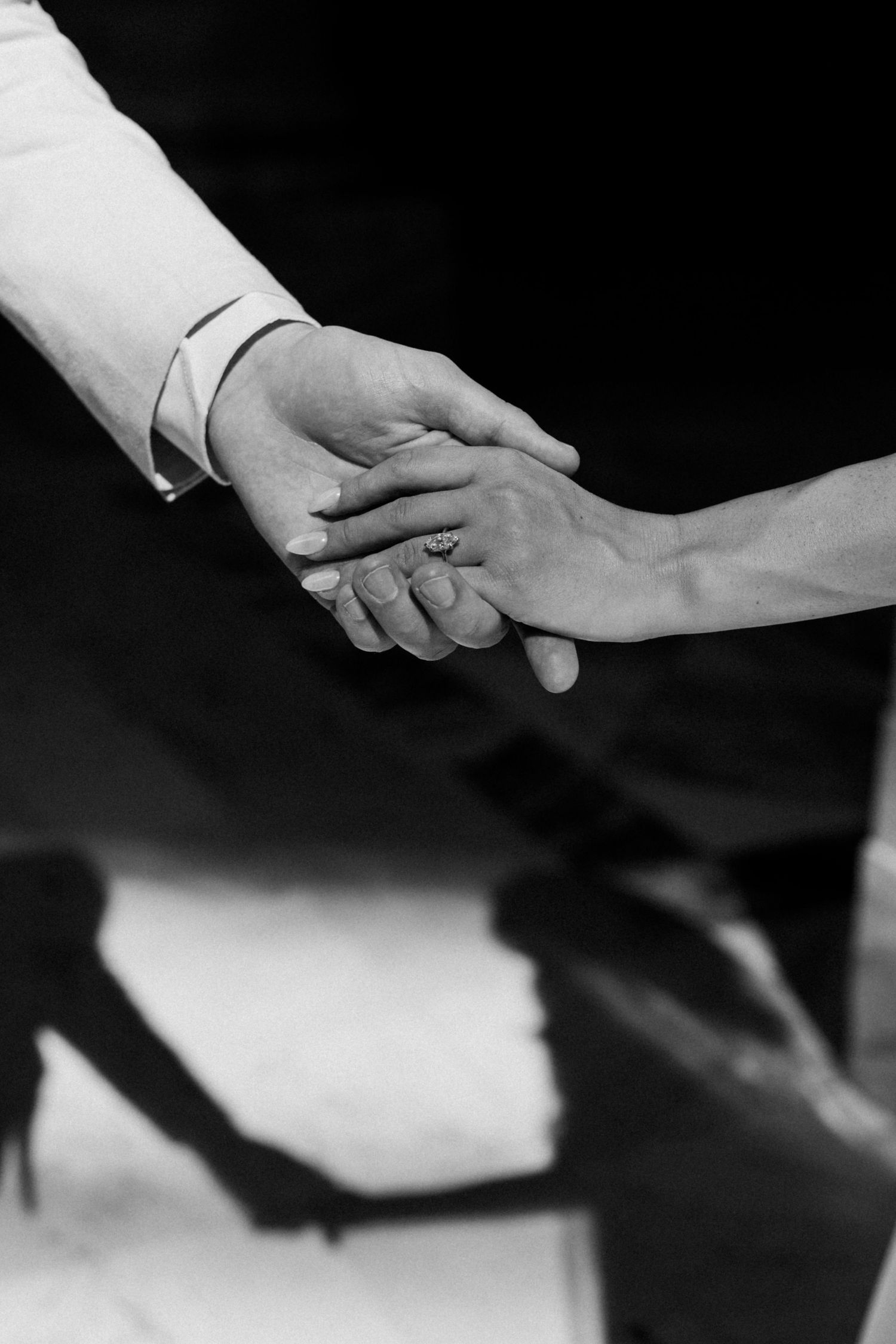 Artistic black and white close-ups of hands touching during a wedding ceremony.
