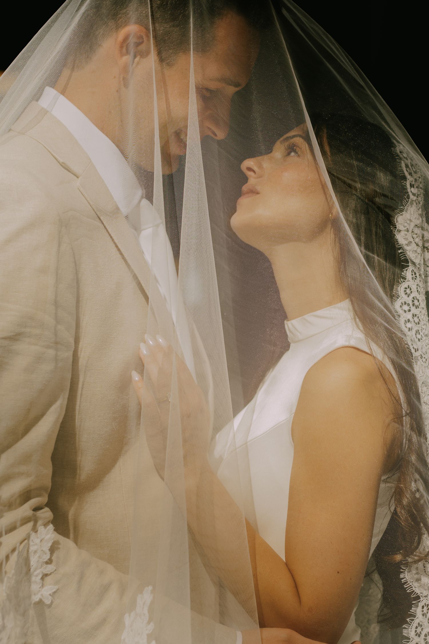Artistic close-up wedding photo with dreamy lighting and veil details.