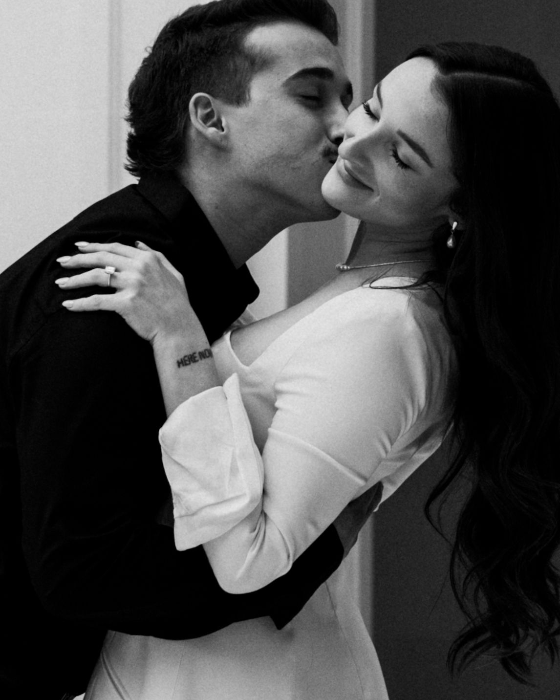 A romantic black and white portrait captures an intimate moment between two people.
