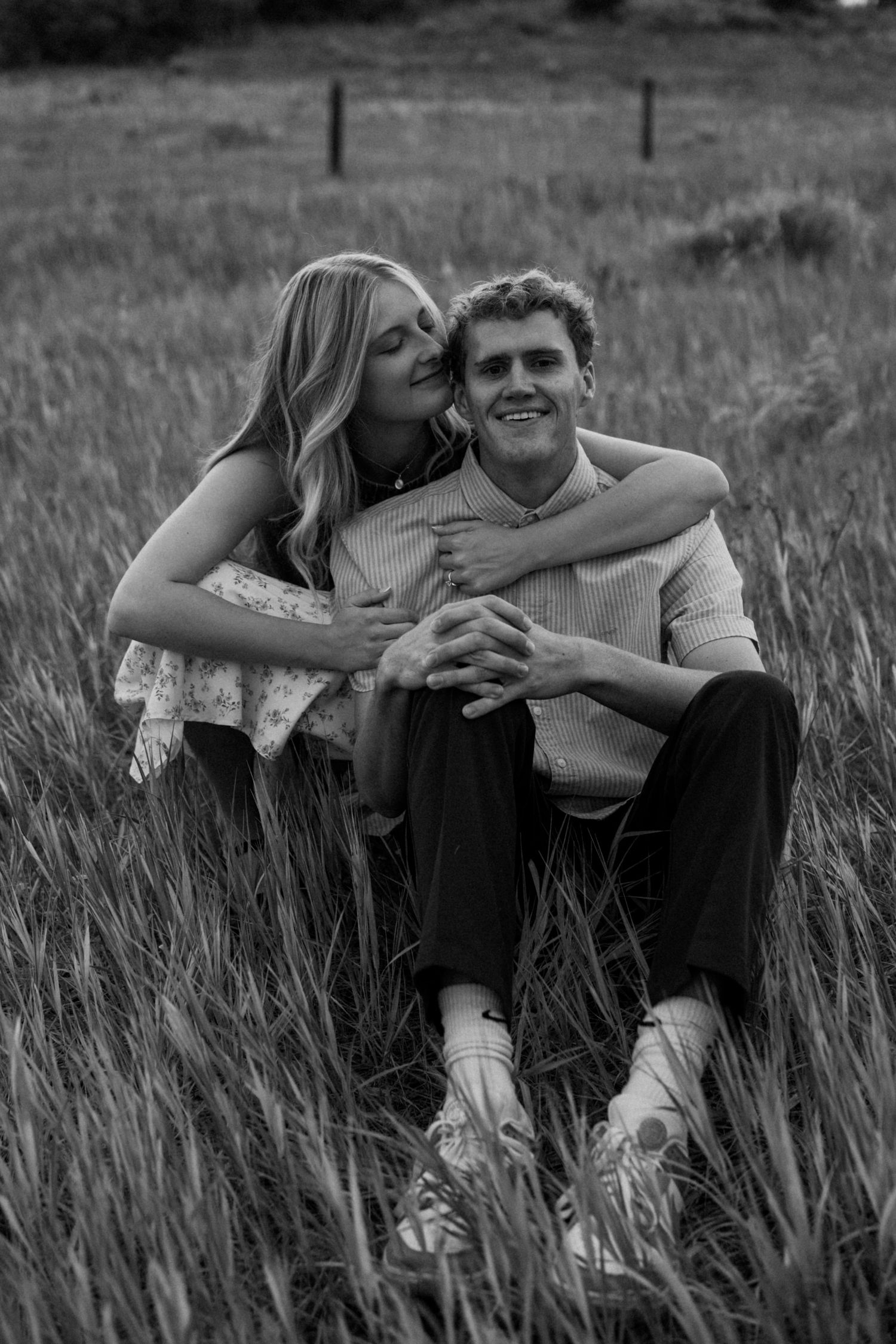 Black and white series of intimate moments between a couple lounging in a grassy meadow.