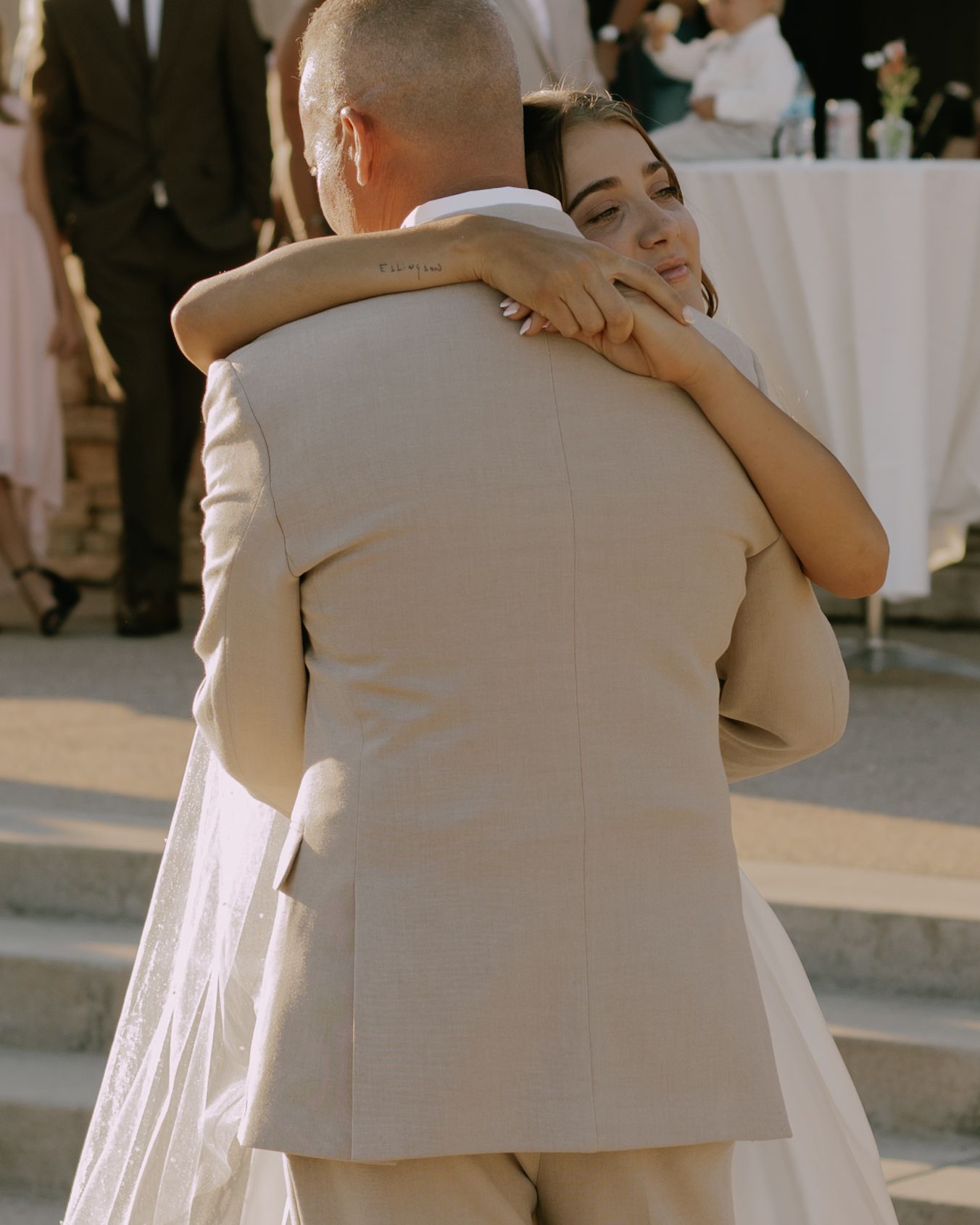 Newlyweds share emotional embrace during outdoor wedding reception.