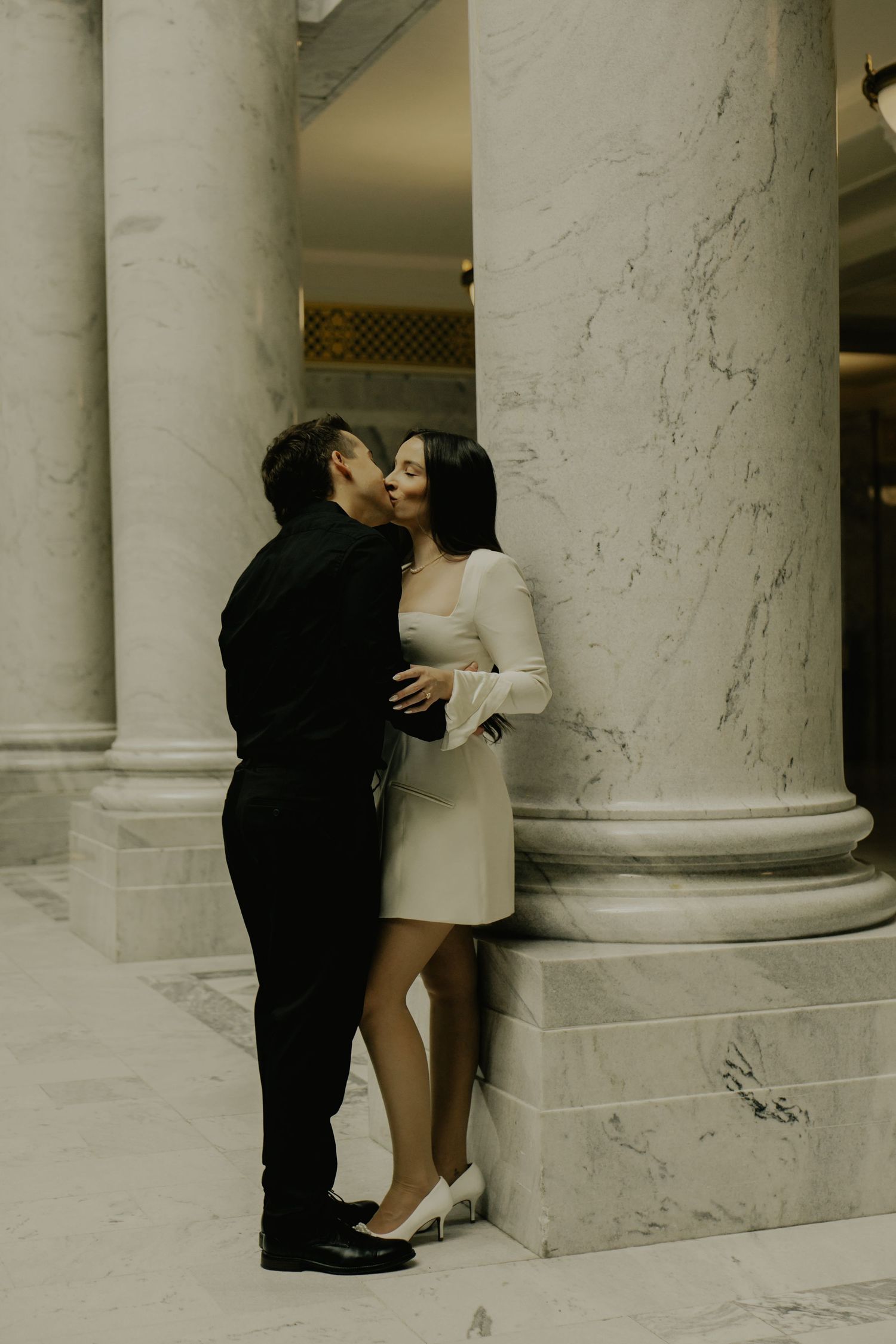 Artistic black and white photo series showing a couple embracing between classical marble columns.