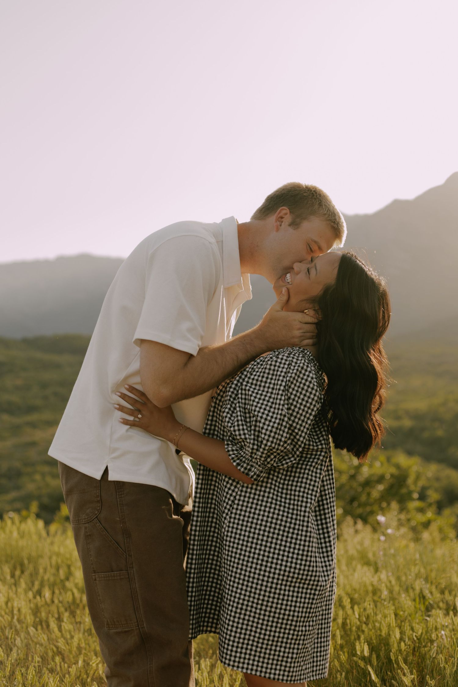 A romantic sequence captured in golden sunlight with mountains and tall grass in the background.