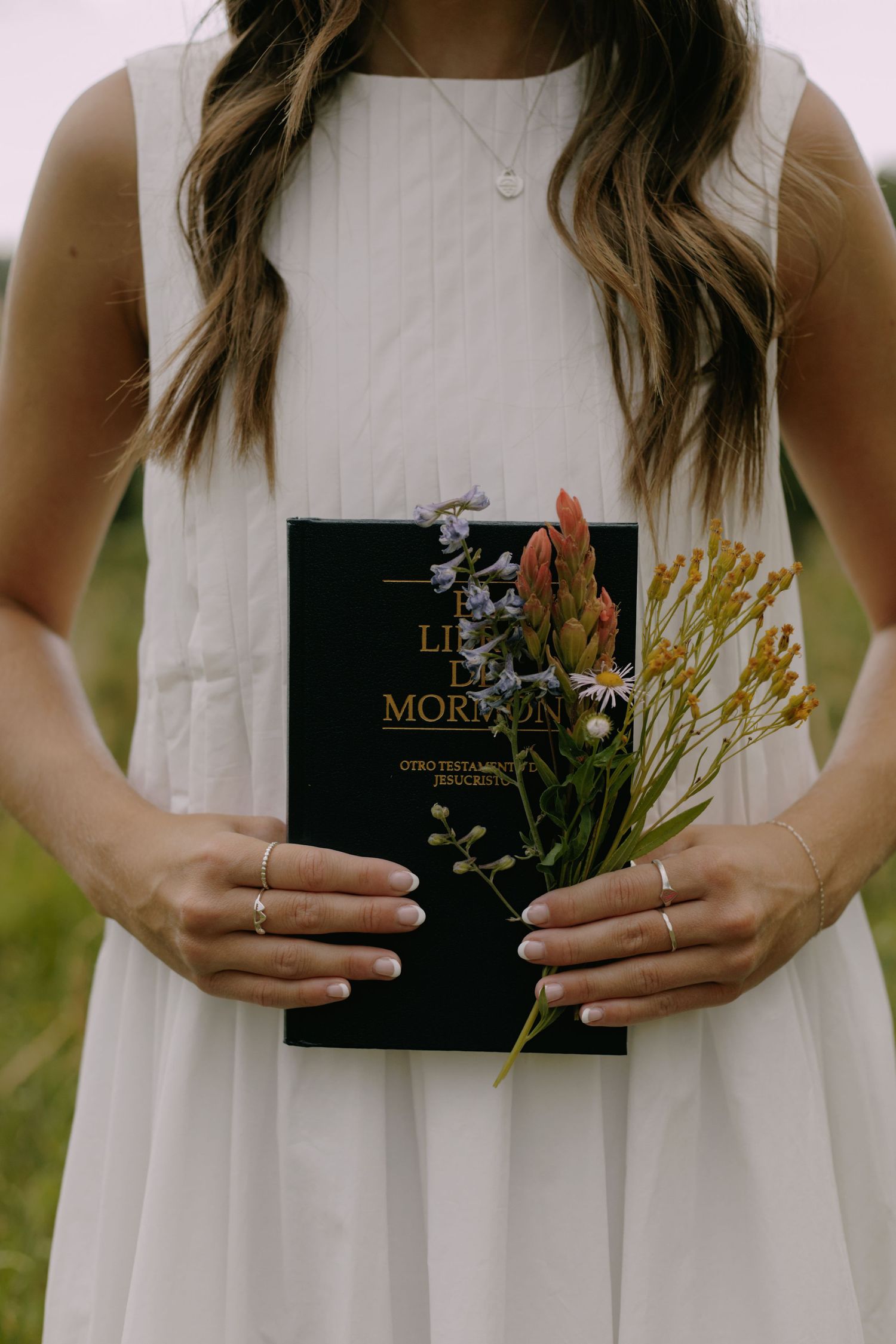 Hands hold a black Morgan book against a white dress in an outdoor setting.