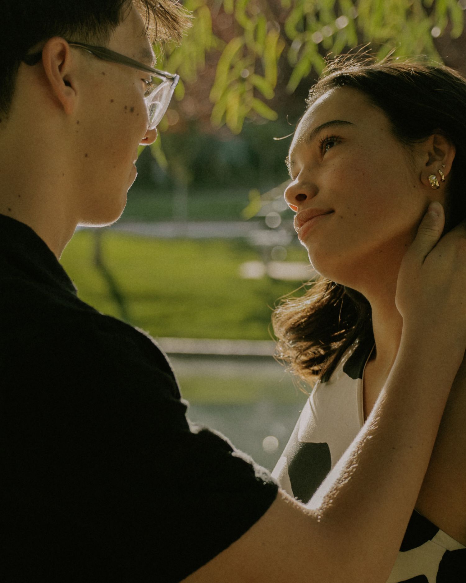 Romantic couple sharing intimate moments in golden sunlight at a park.