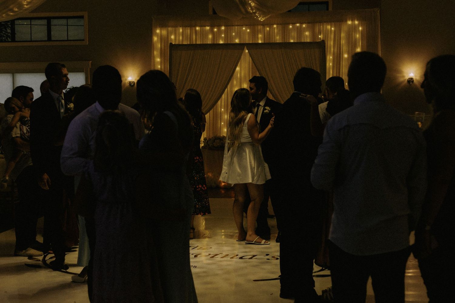 Wedding reception dance floor with guests celebrating under warm lighting.
