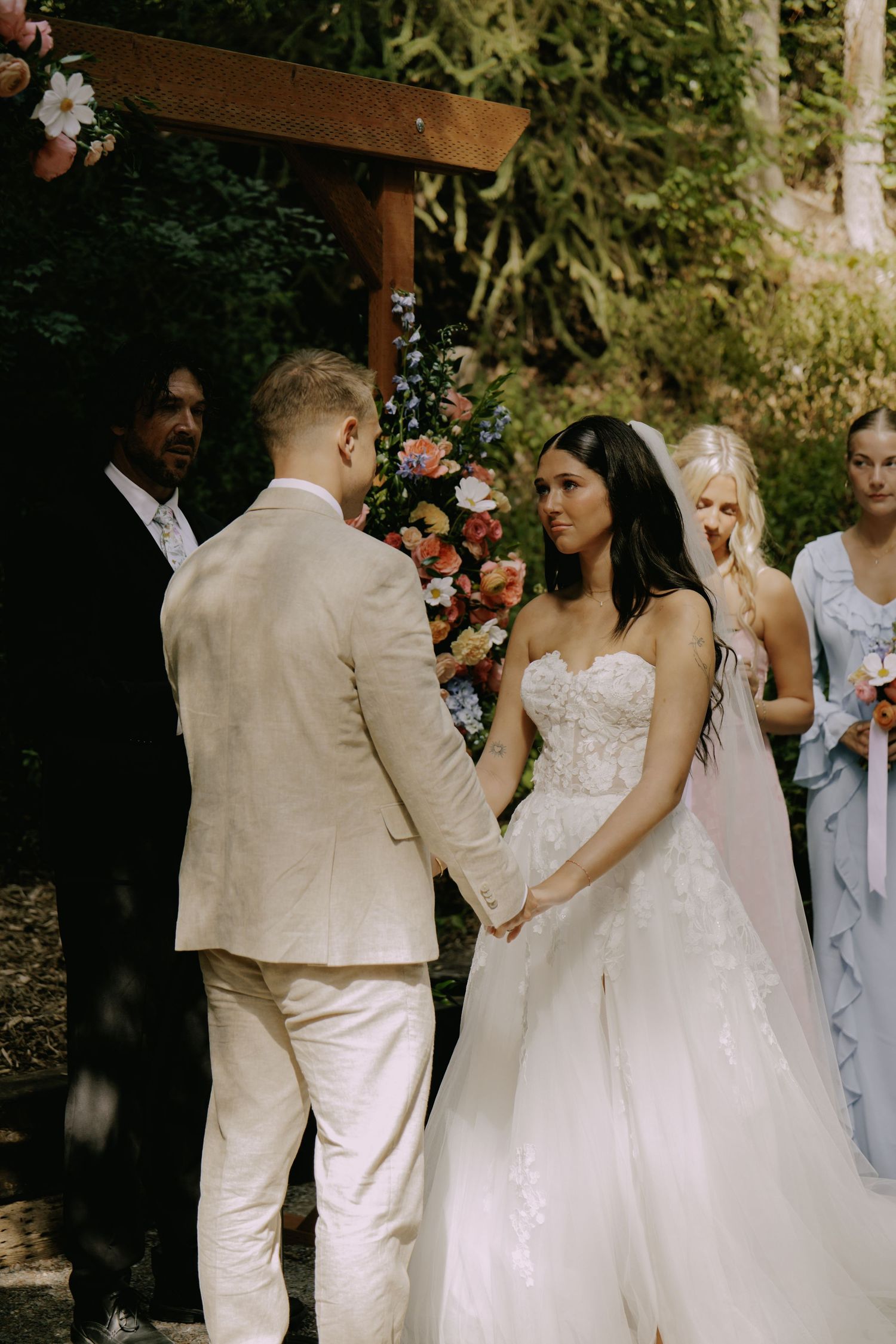 Wedding party gathered outdoors in white and light-colored attire.