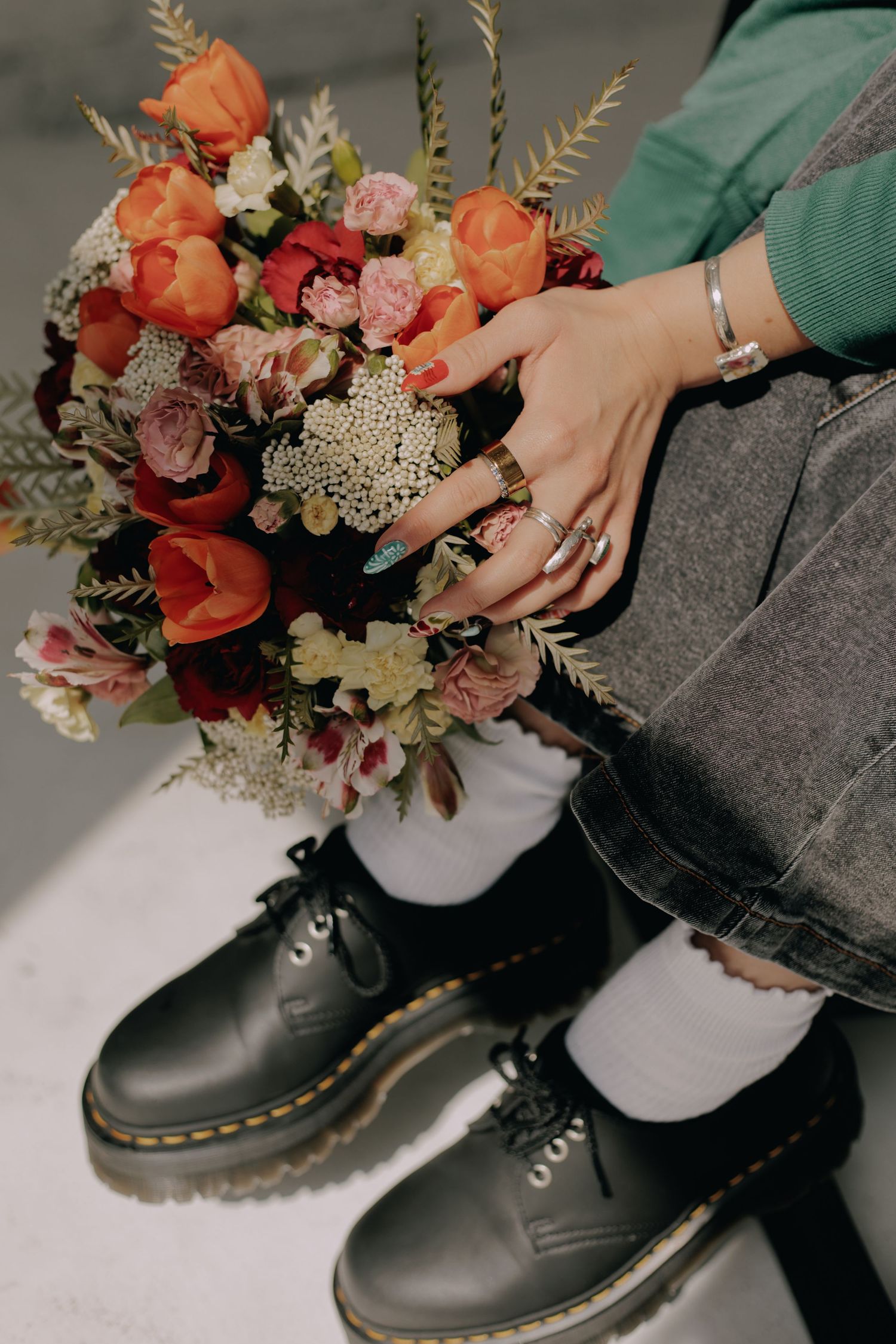 Black combat boots paired with a colorful floral arrangement on a white surface.