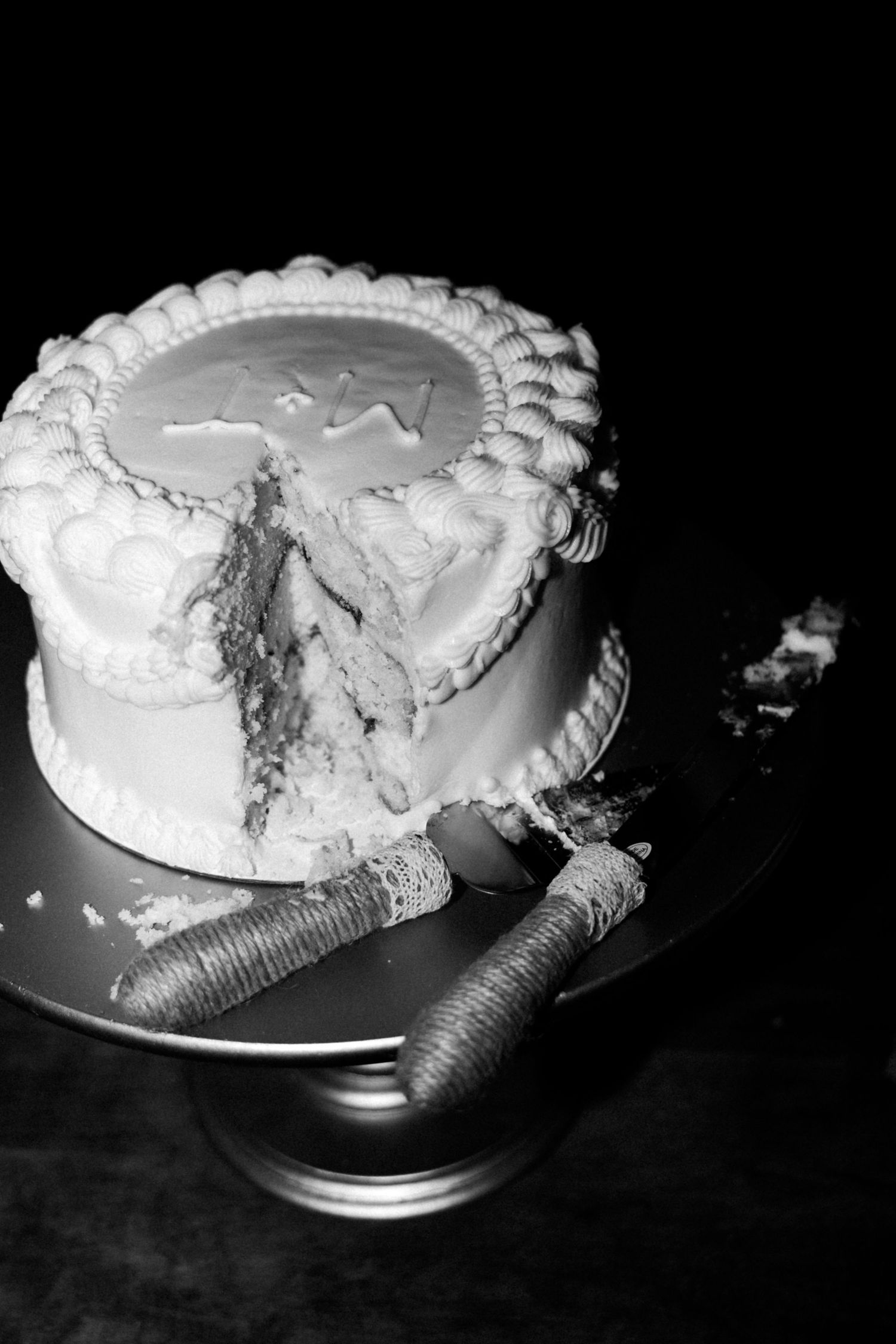 A sequence of black and white photos showing a wedding cake being cut.