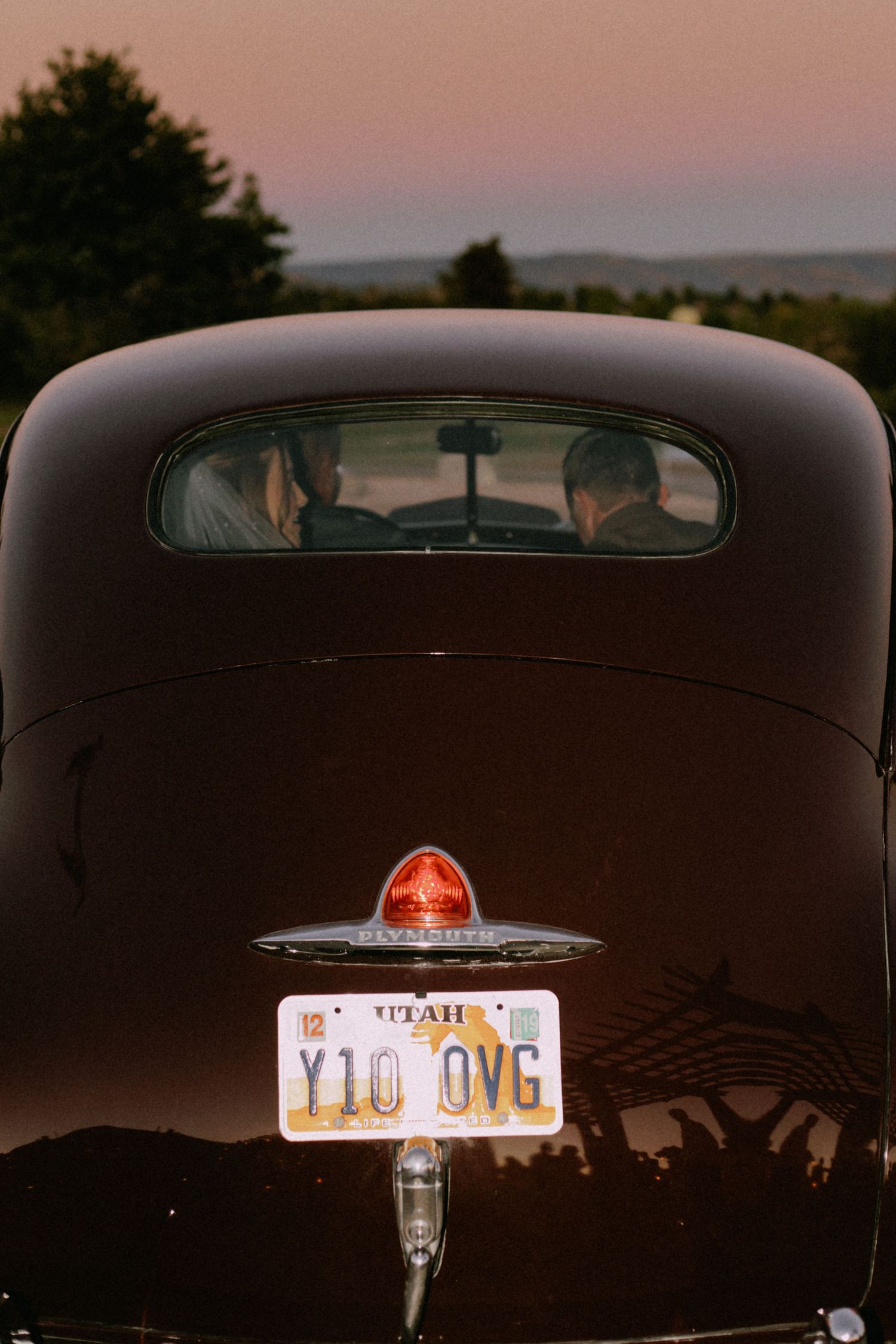 Classic vintage car with illuminated license plate photographed at dusk.