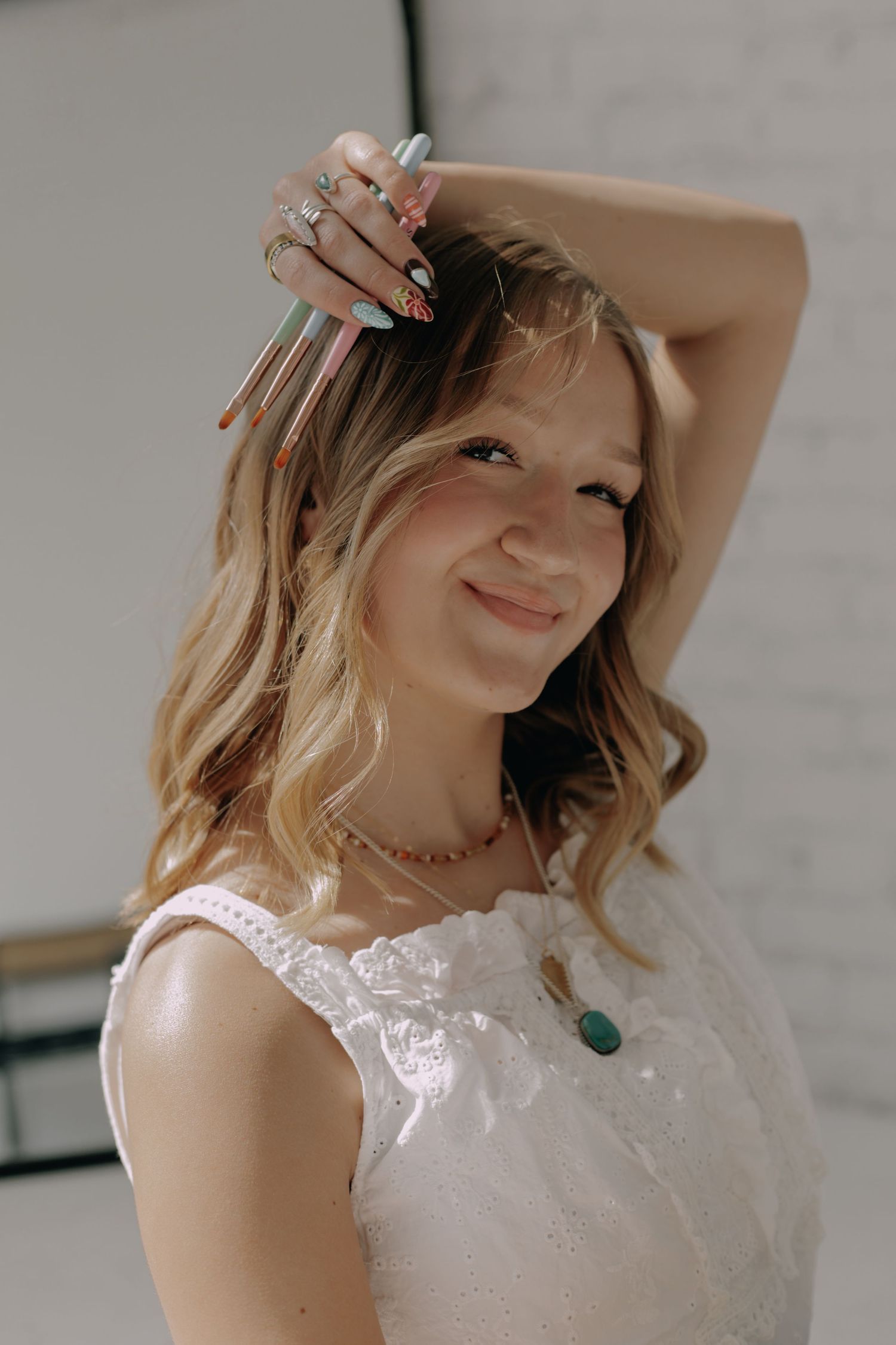 Elegant portrait featuring someone in a white lace dress with a turquoise necklace against a light background.