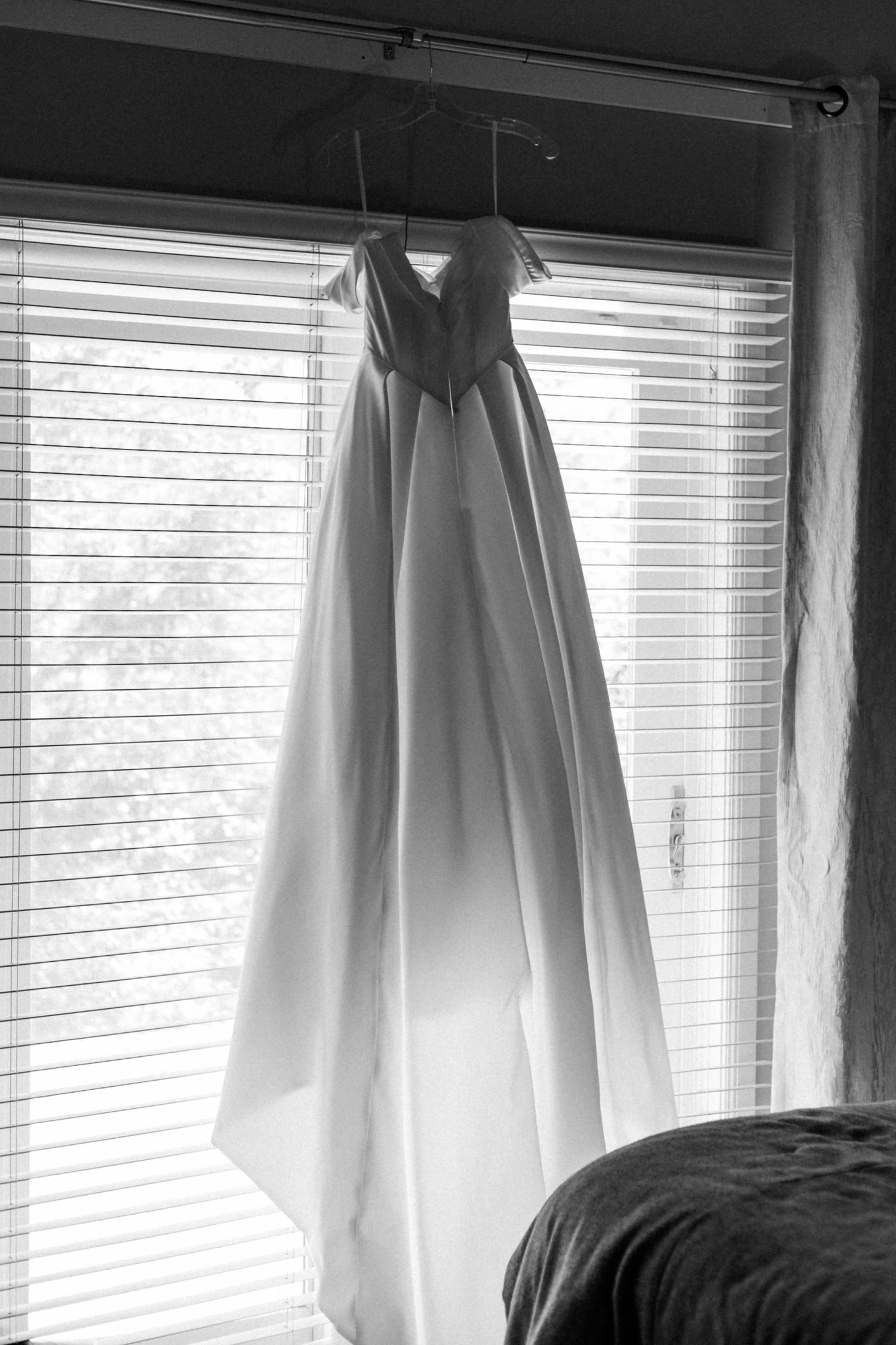 White curtains and blinds frame a bright window in a modern bedroom.
