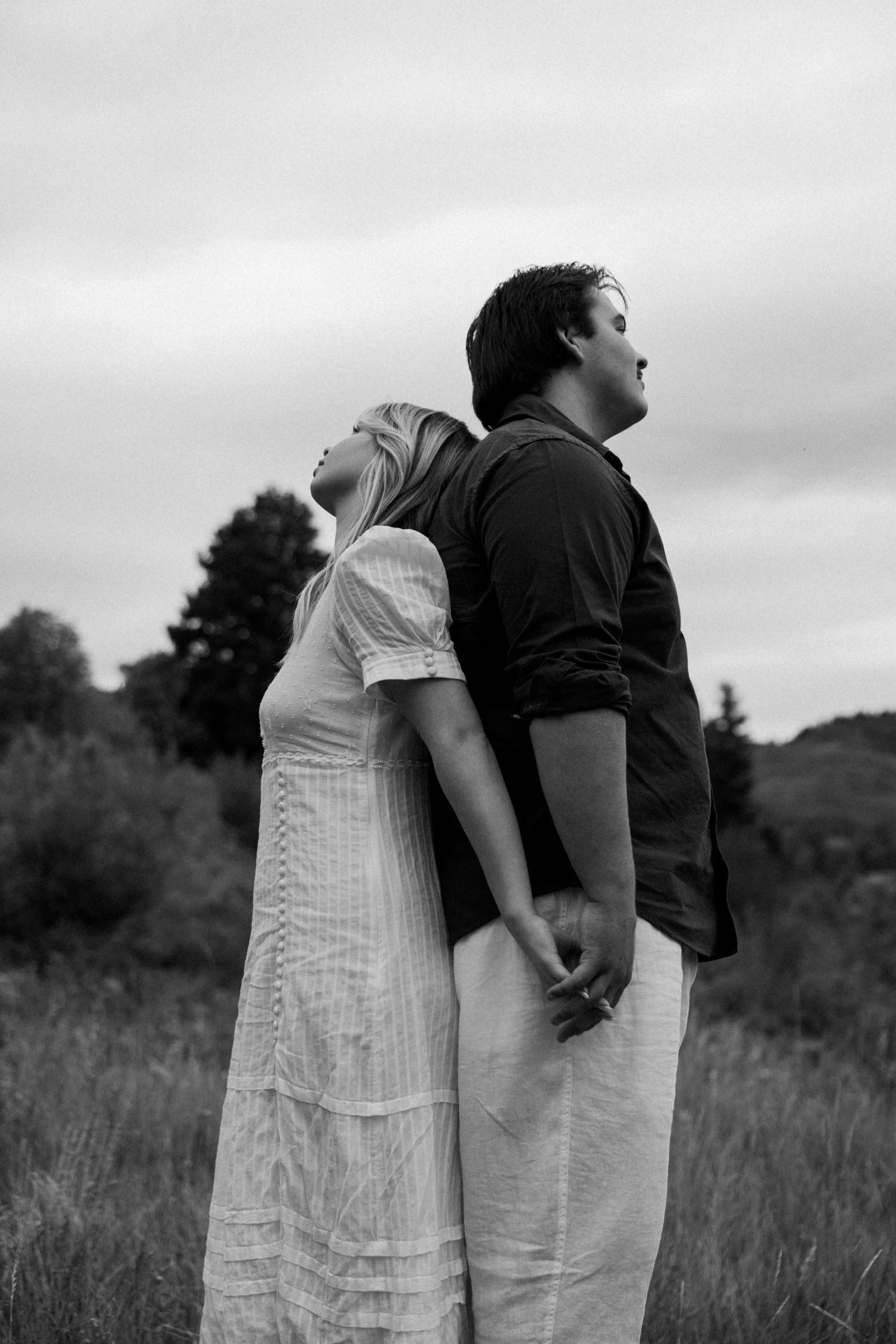 Artistic black and white portrait series showing intimate moments between a couple in a field.