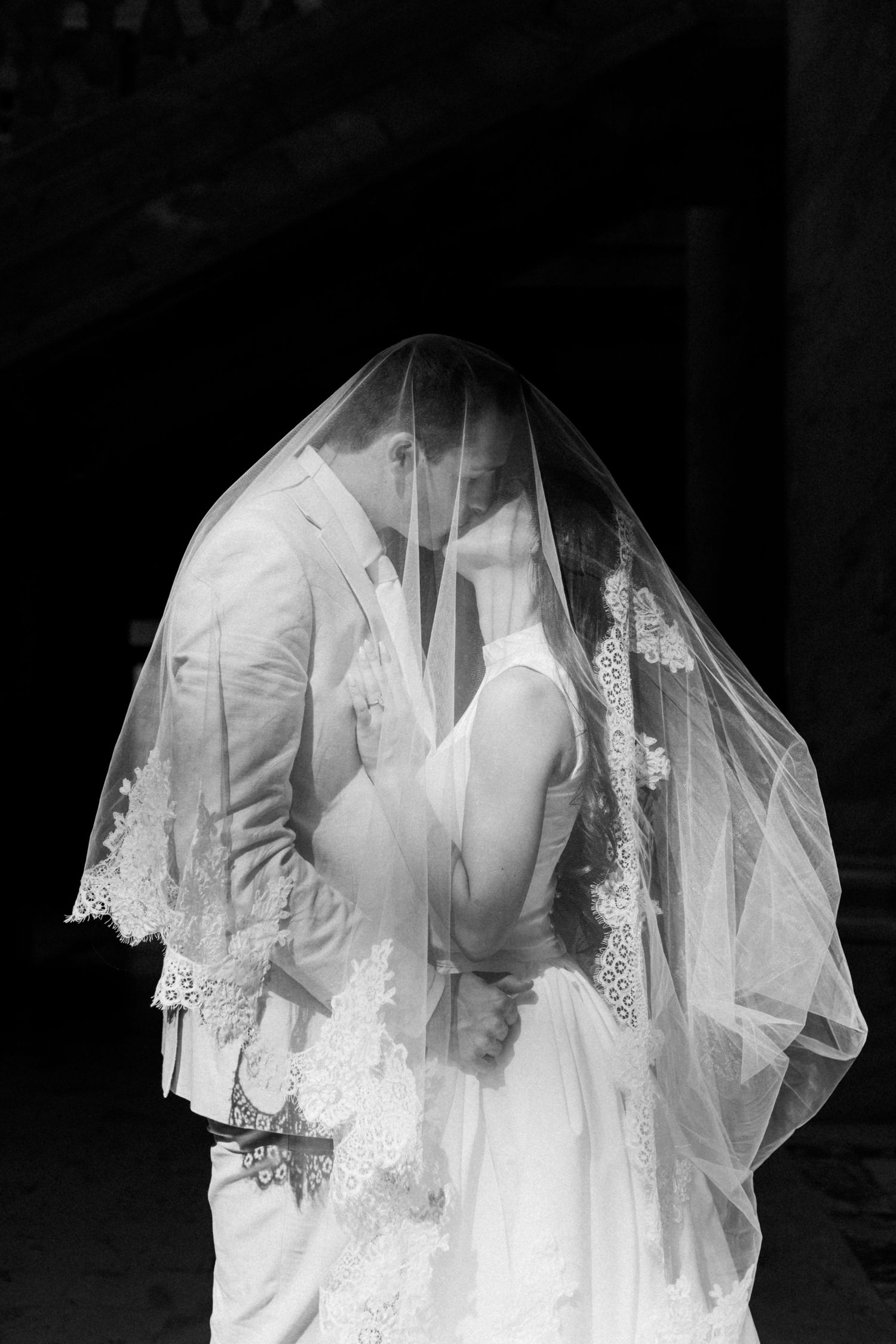 Ethereal black and white wedding photo featuring delicate veil details and intimate embrace.