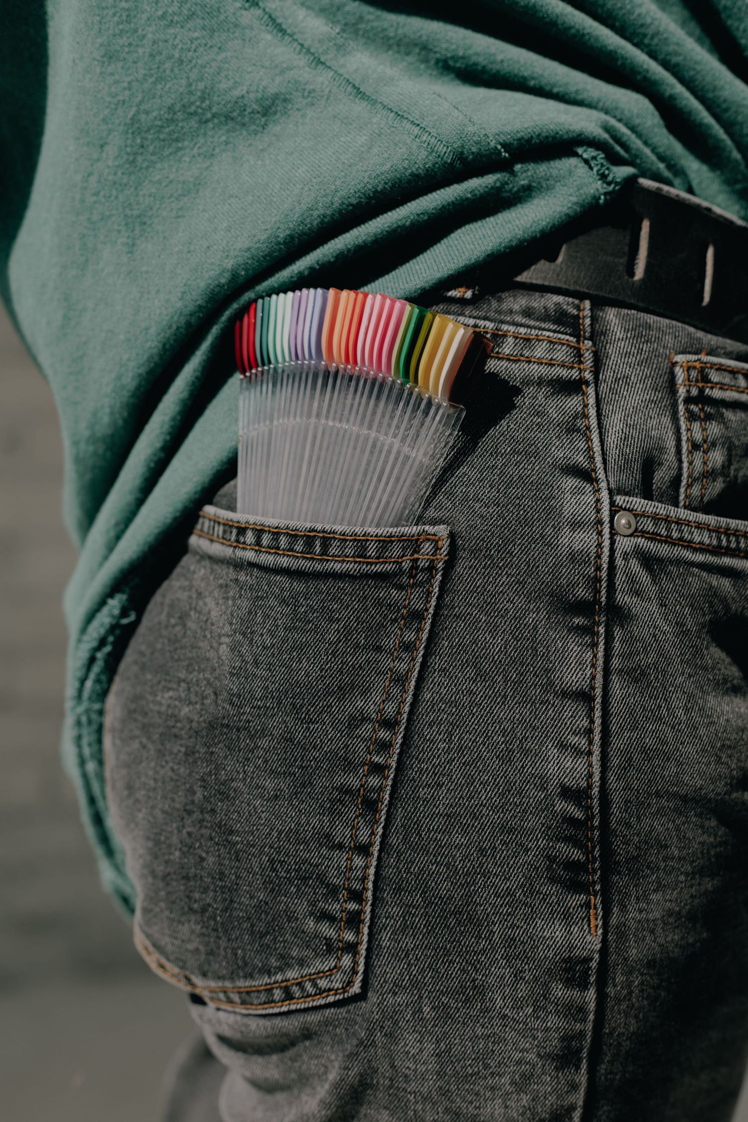 Close-up of back pocket of dark jeans with colorful items peeking out.