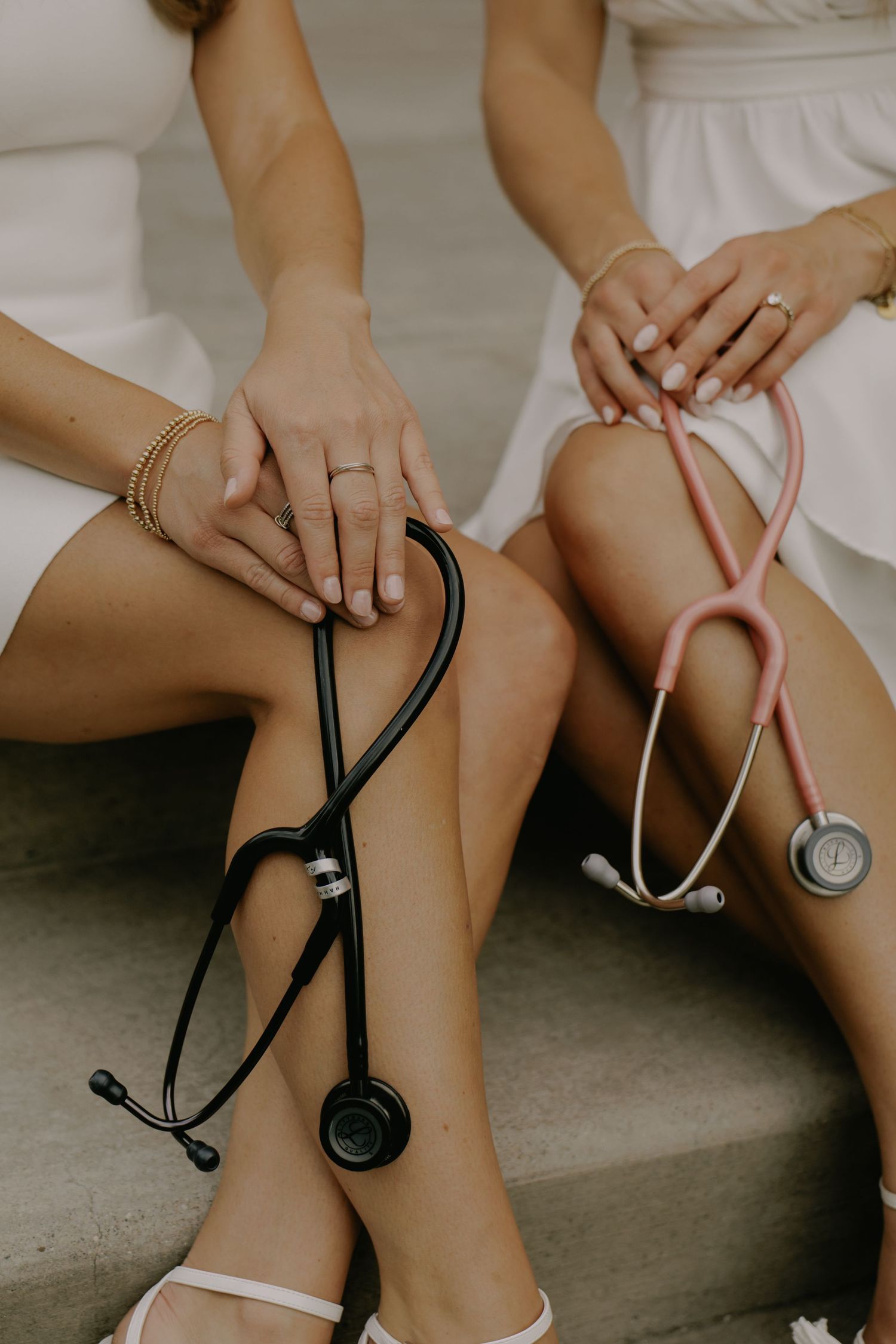 Medical professional's hands holding stethoscope while sitting in white dress.