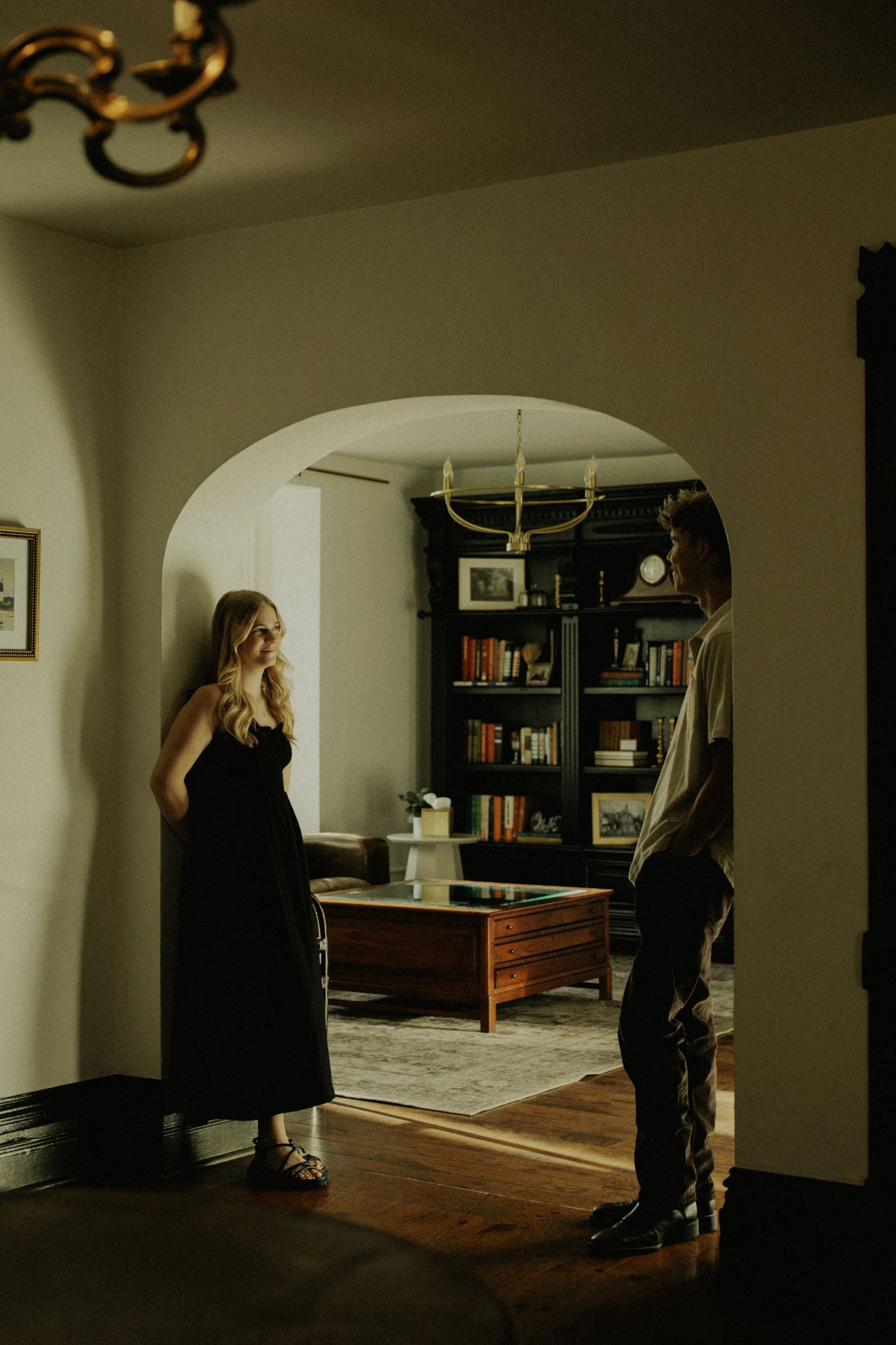 Moody indoor photoshoot in a dimly lit room with arched doorways.
