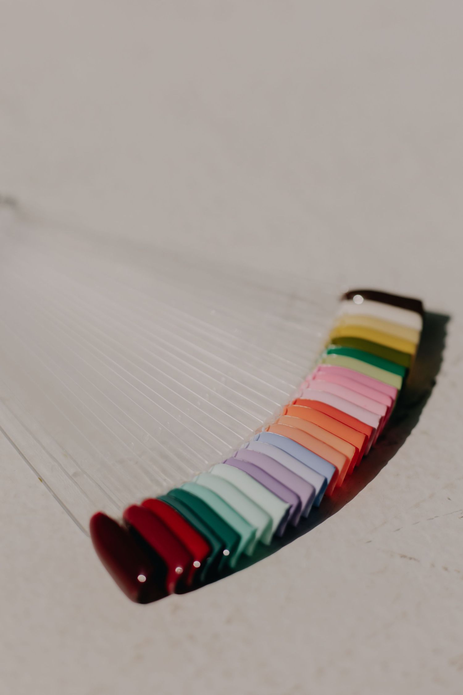 Colorful spools of thread arranged in rainbow gradient pattern on light surface.