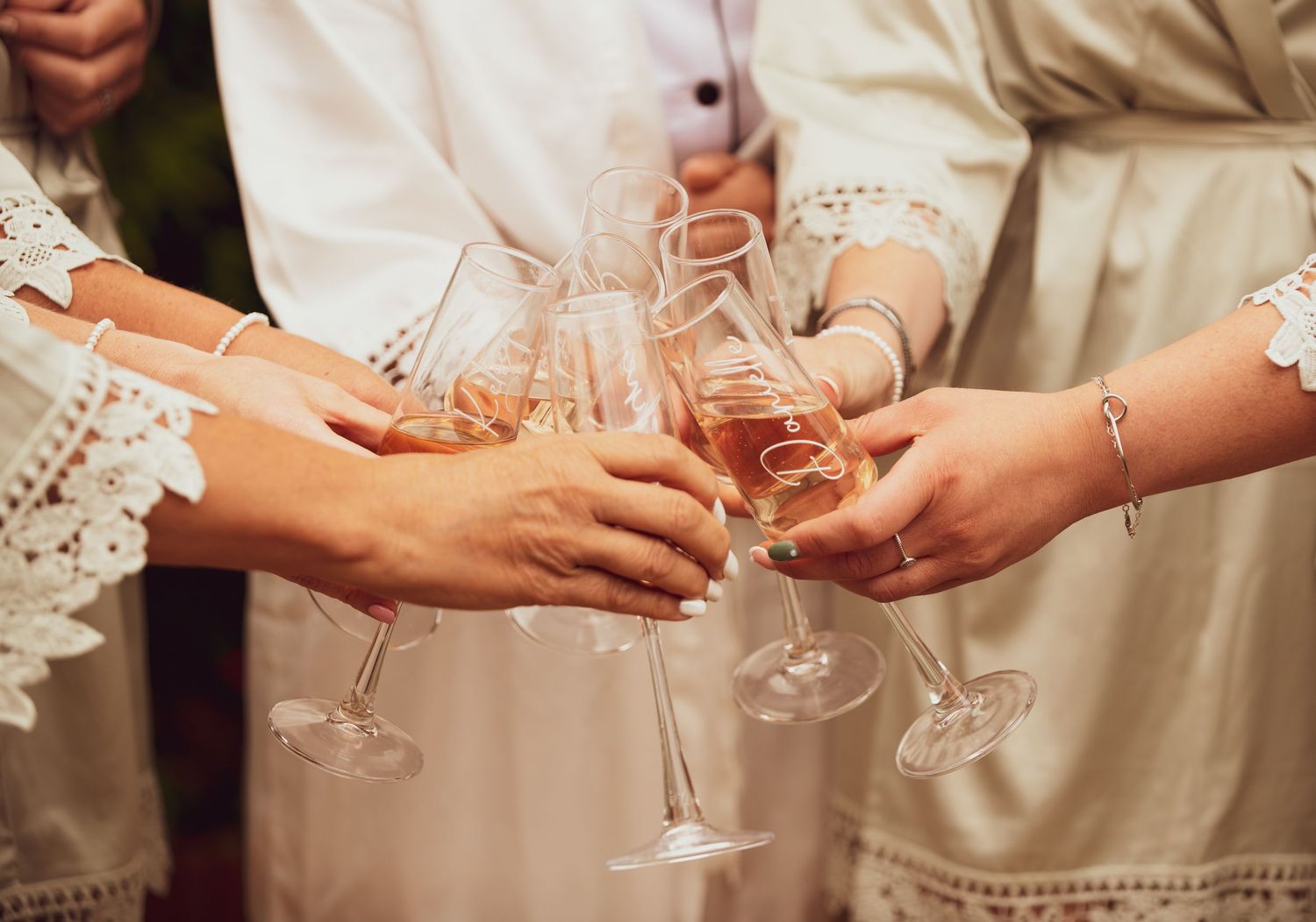 Wedding guests clink glasses of rose champagne in celebratory toast at reception.