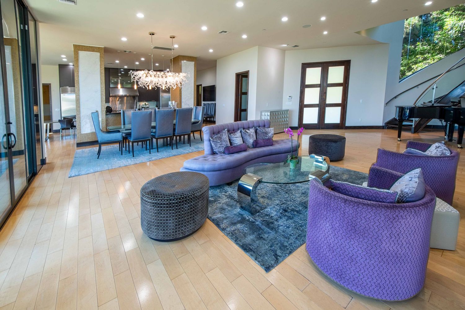 Modern open concept living space featuring purple velvet accent chairs and light hardwood floors with recessed lighting.