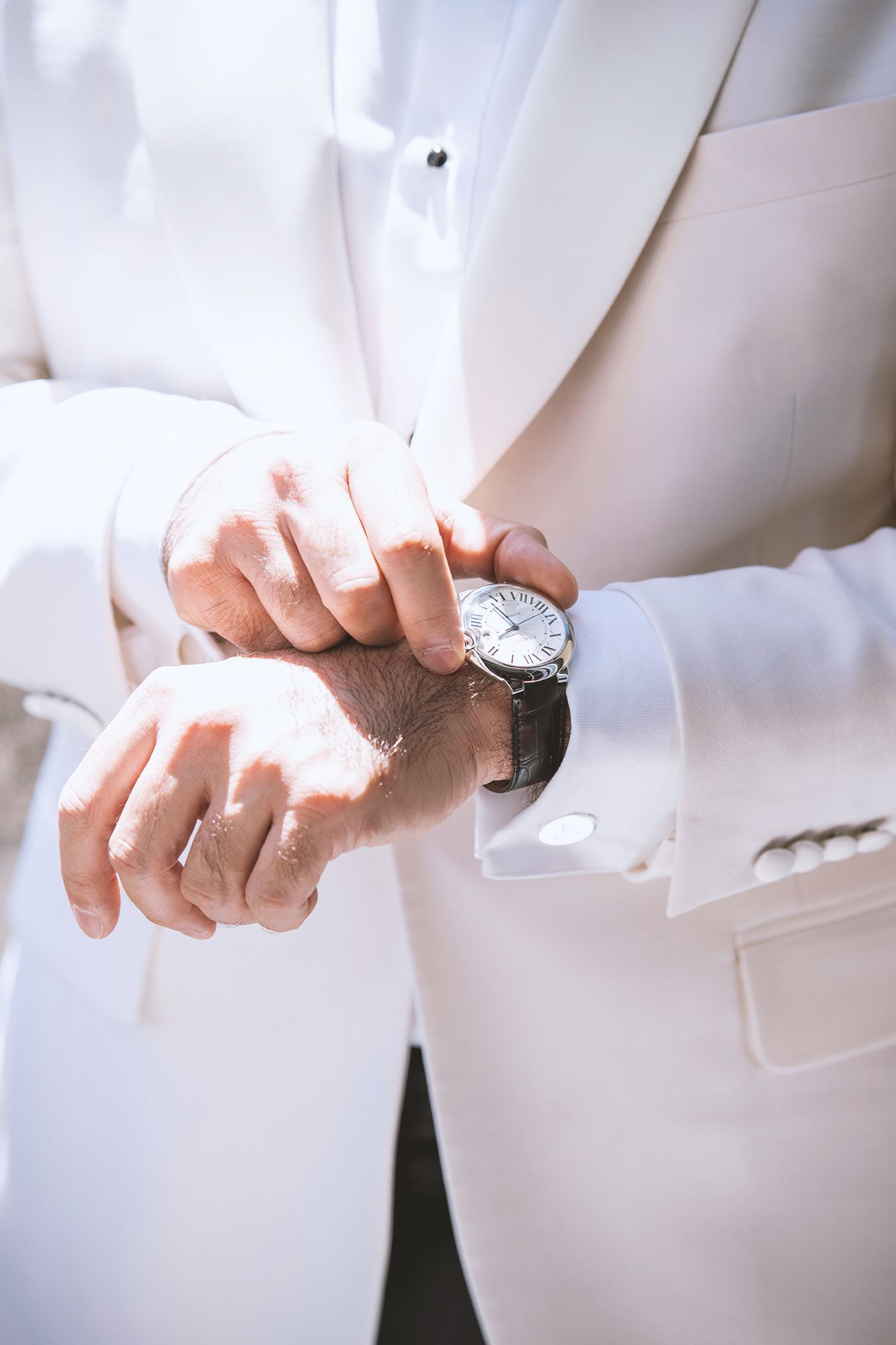 Close-up shots of hands adjusting a white dress shirt sleeve and wristwatch in a formal setting.