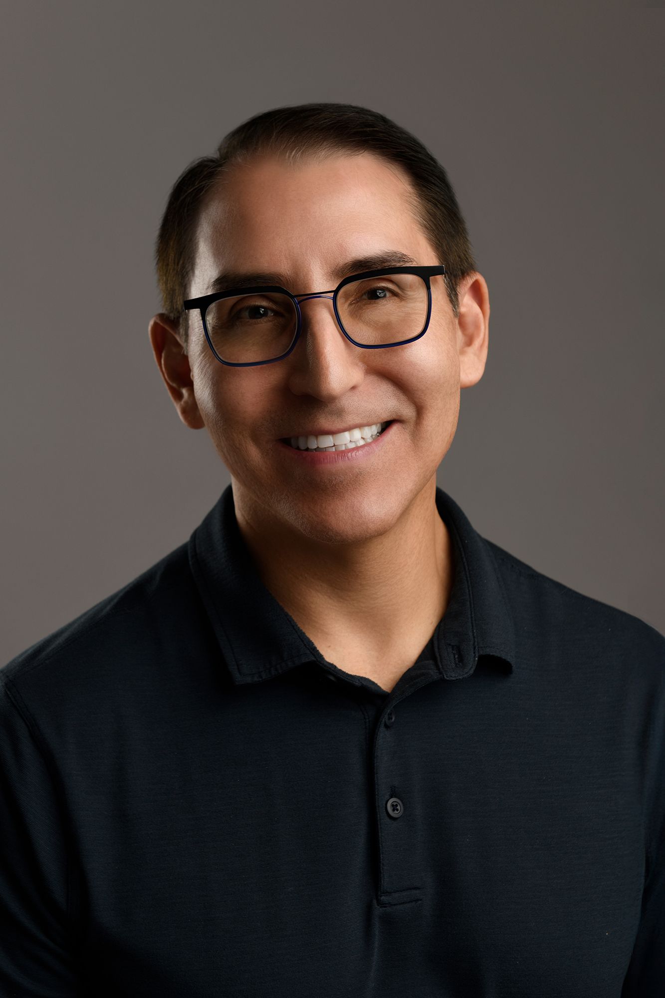 Professional commercial headshot of smiling man wearing glasses and dark polo shirt taken in west Los Angeles.
