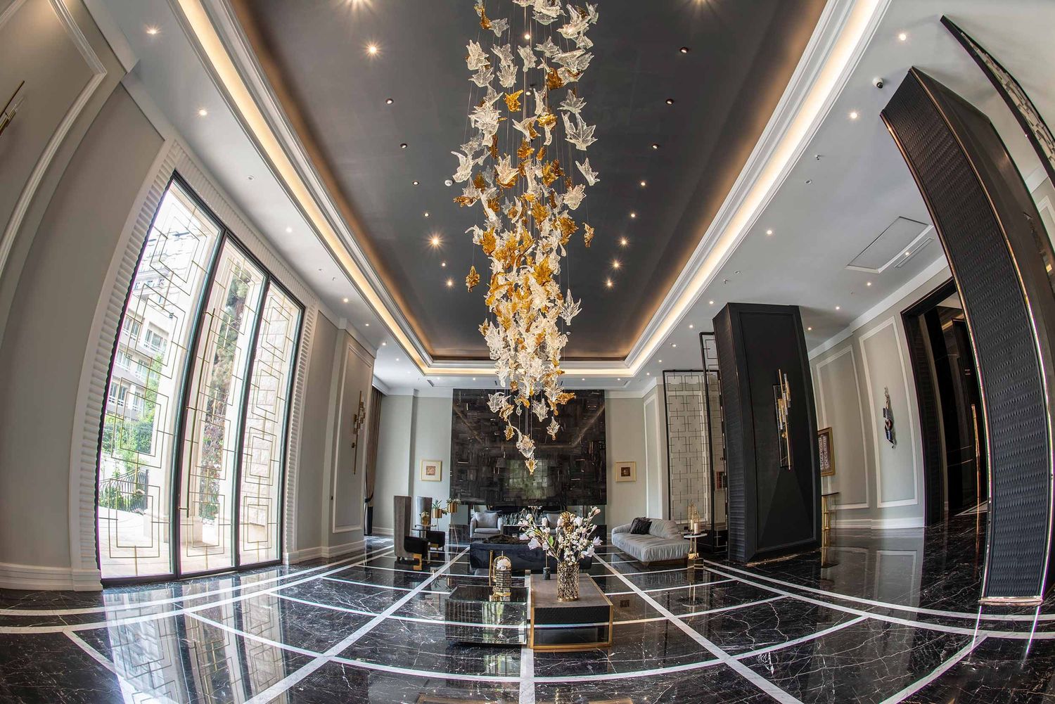Luxurious hotel lobby interior with dramatic golden chandelier and reflective marble floors creating an elegant atmosphere.